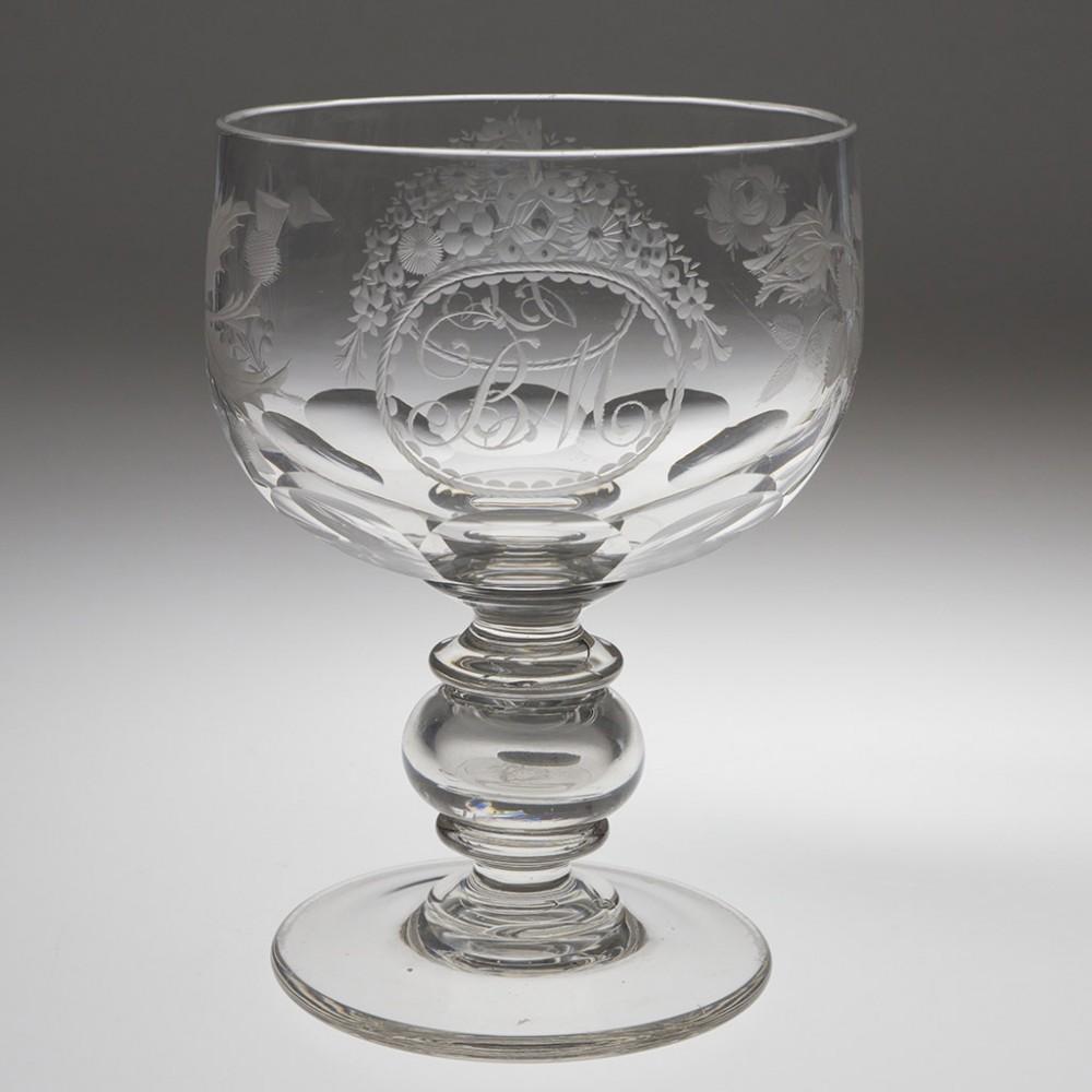 Heading : Victorian coin goblet
Period : c1840
Origin : England
Colour : Clear
Bowl : Cup shaped with large lens cutting to base. Engraved with a flowering rose and thistle, the monograms BM and IC both within cartouches with floral decoration.
Stem