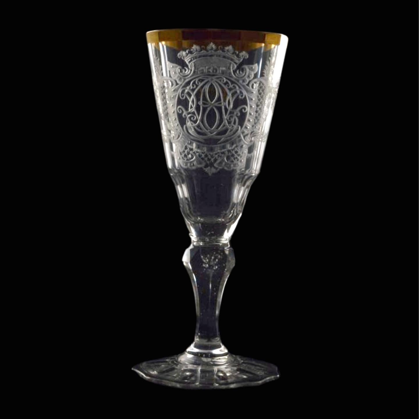 A gorgeous conical wine glass with elaborate engraving encompassing a monogram below a crown, and a gilt rim.


Warmbrunn glass, also known as Warmbrunner glass, refers to a type of glassware that originated in the Warmbrunn (now Cieplice