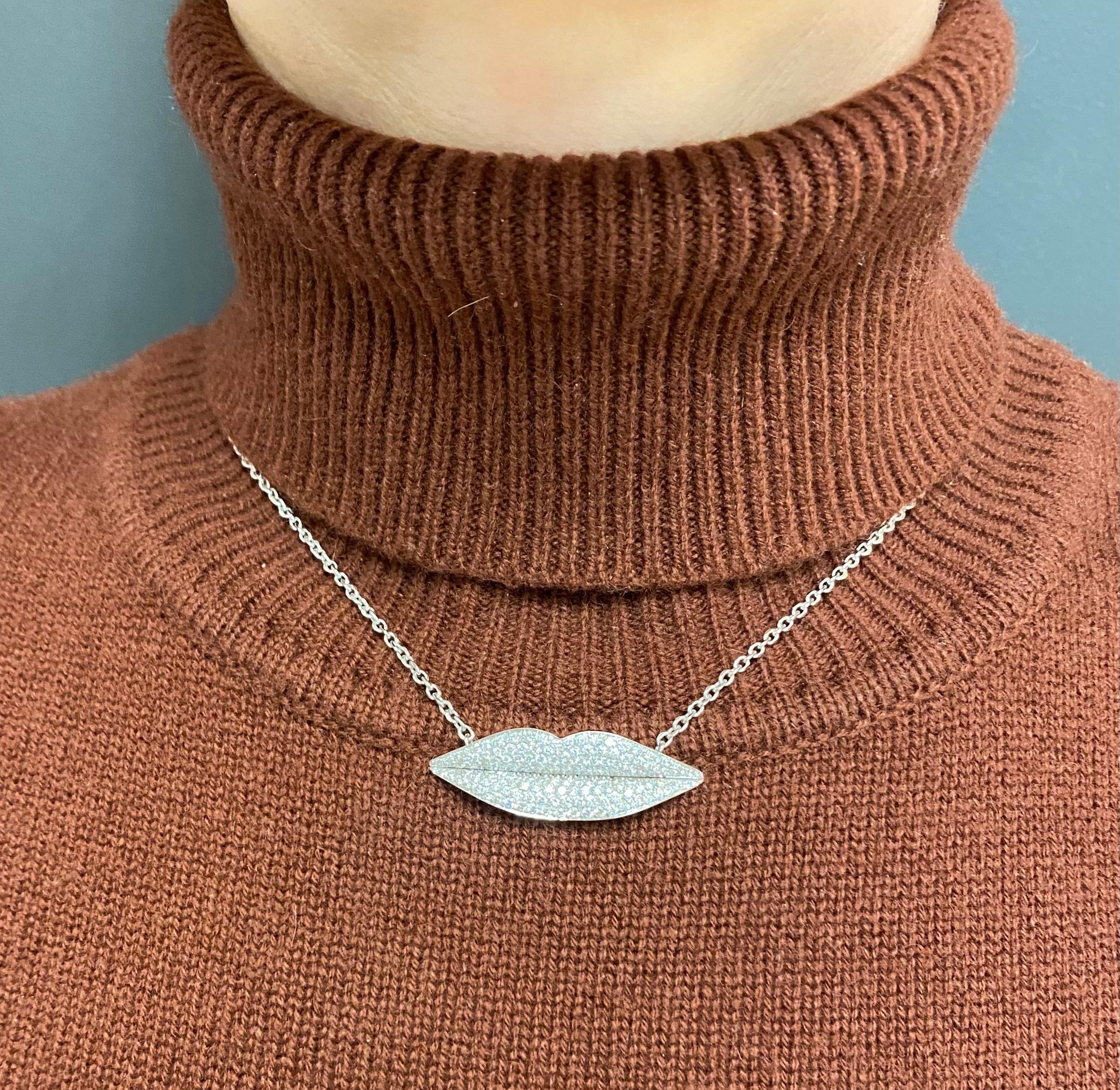 An Enigma by Gianni Bulgari Lips necklace made of 18k white gold, features diamonds.
A sleek lip-shaped pendant, encrusted with diamonds, is suspended from a fine white gold chain. With the delicately outlined lips, this design is playful and