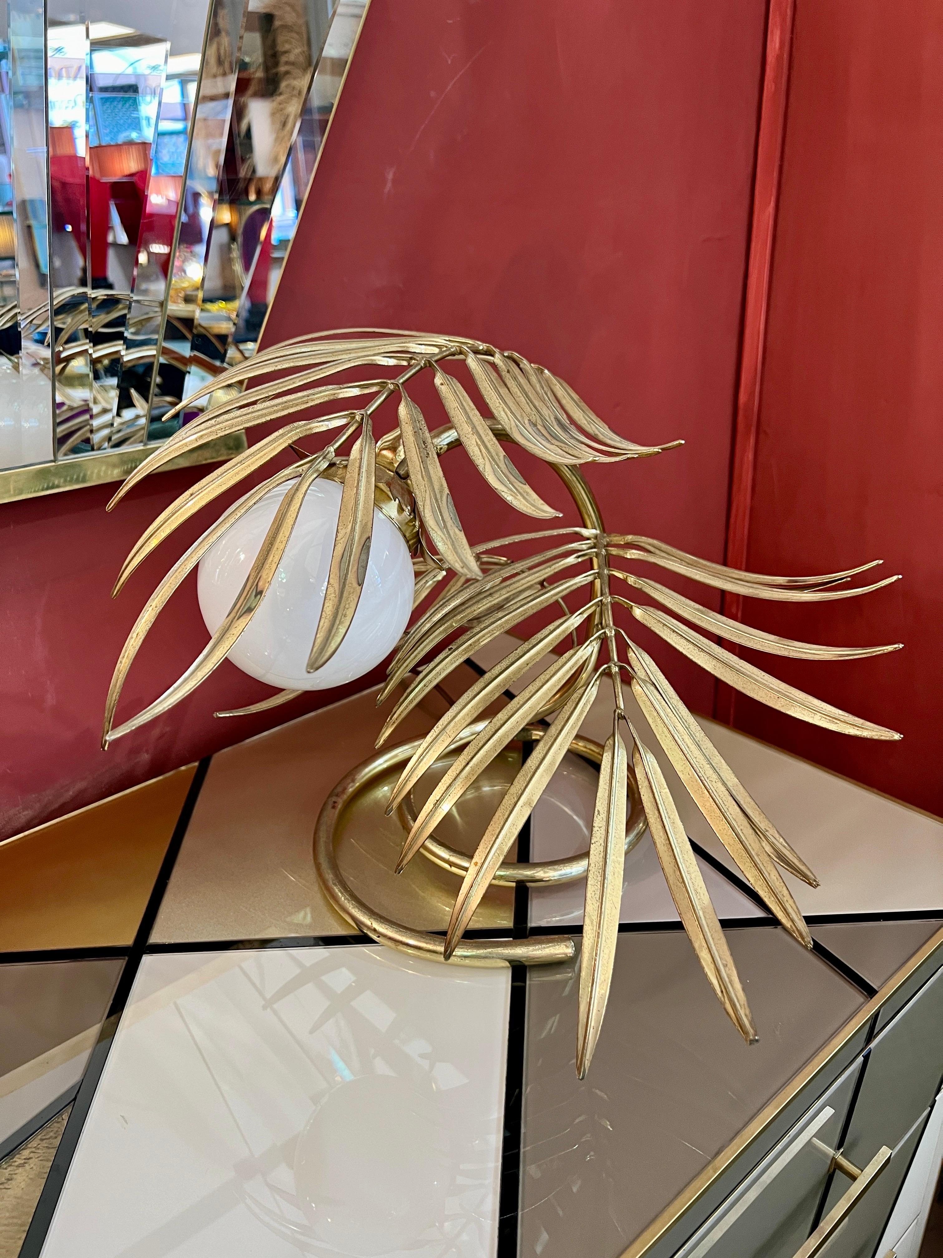 Enlightening plant brass leaves table lamp. This highly decorative table lamp is formed into sharp leaves and a white Murano glass sphere.
One light bulb.
The metal is original of the period and thus shows normal signs of age and use which increases