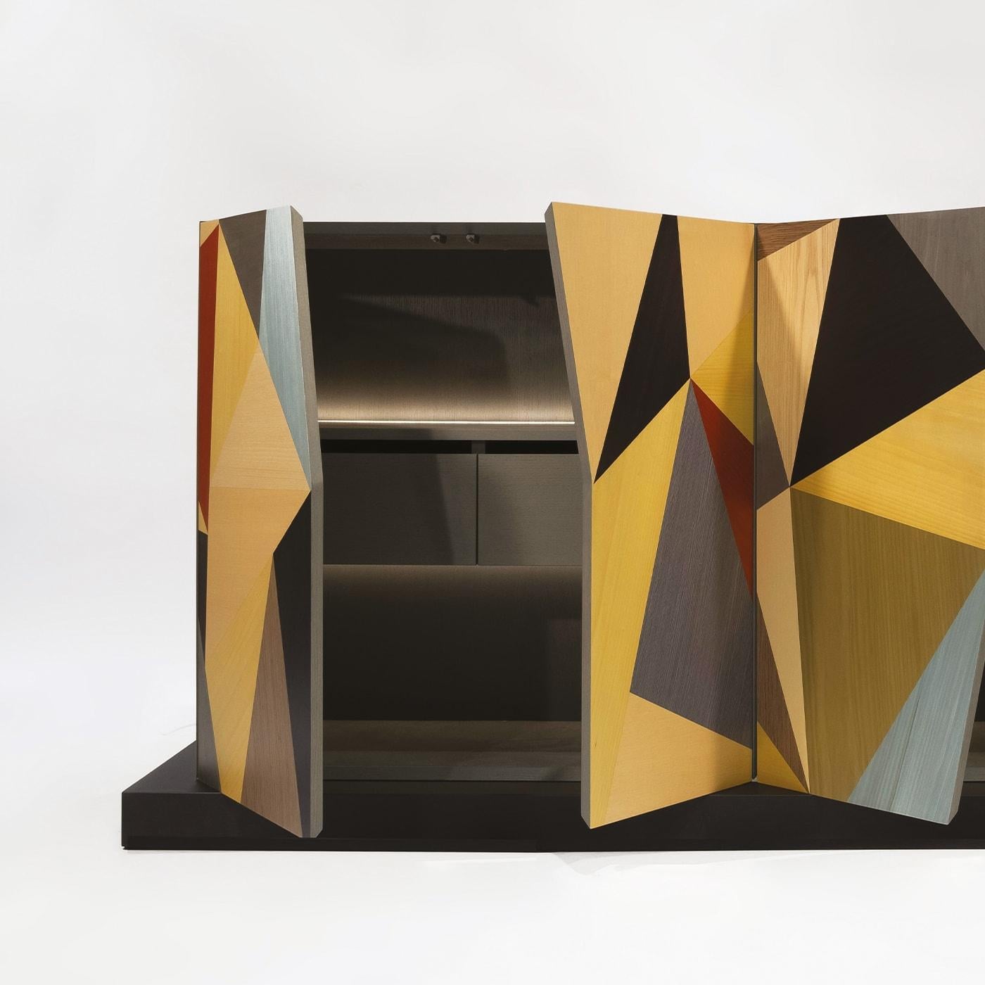 Das totemistische Sideboard Enna, inspiriert von der modernen und zeitgenössischen Kunst Siziliens, kann dank seiner fünf sichtbaren Seiten überall aufgestellt werden. Die polychromen Holzeinlegearbeiten mit ihrem minimalistischen Design erinnern