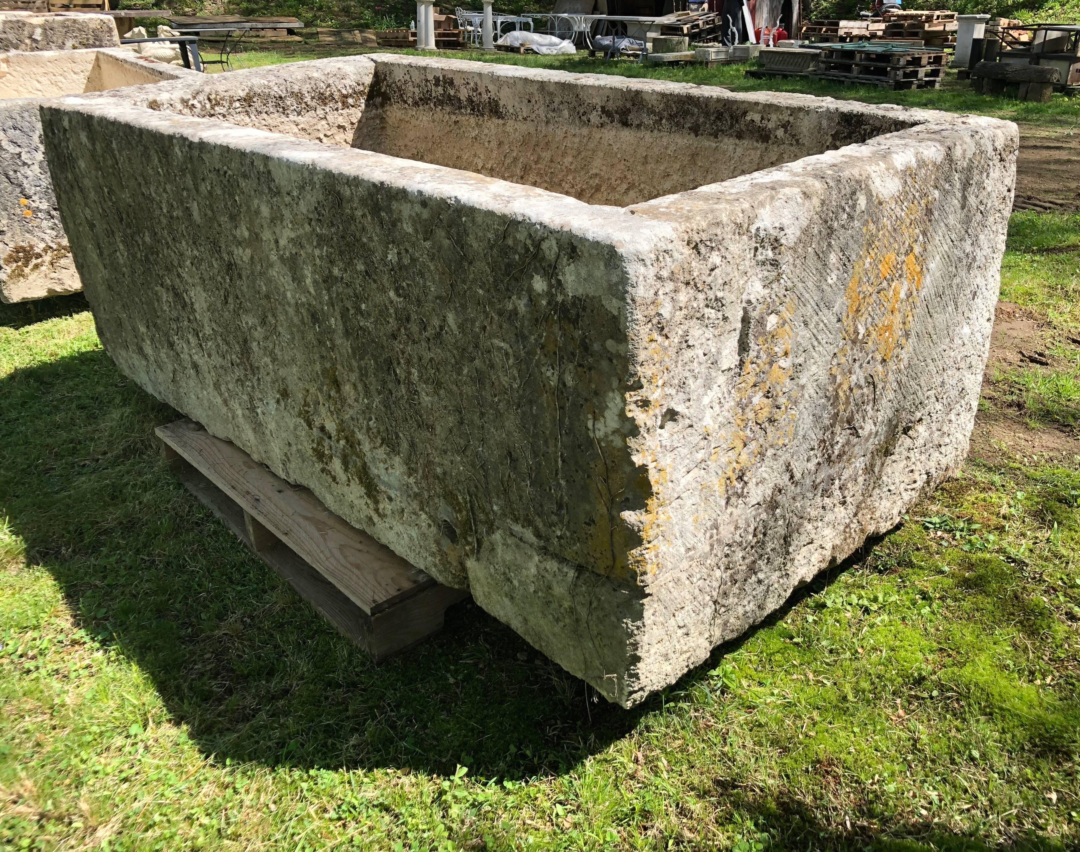 Cette magnifique et très grande auge en pierre calcaire sculptée à la main présente une patine crème pâle avec du lichen et quelques résidus de lierre. Le bord inférieur intérieur avait été recouvert d'une couche de ciment de couleur assortie (telle