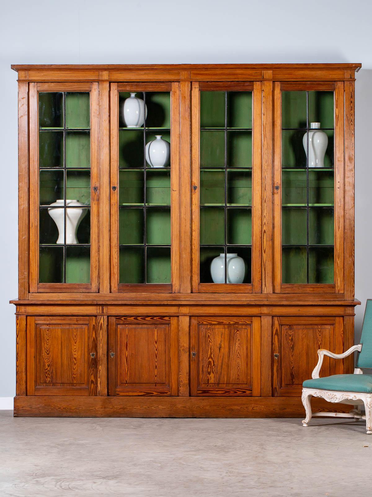 This stunning and enormous antique French pine cabinet bibliotheque is a true rarity. Constructed in two parts, a top that sits on the base, the four upper glass doors retain their original panes of handcut and hand set glass within the original