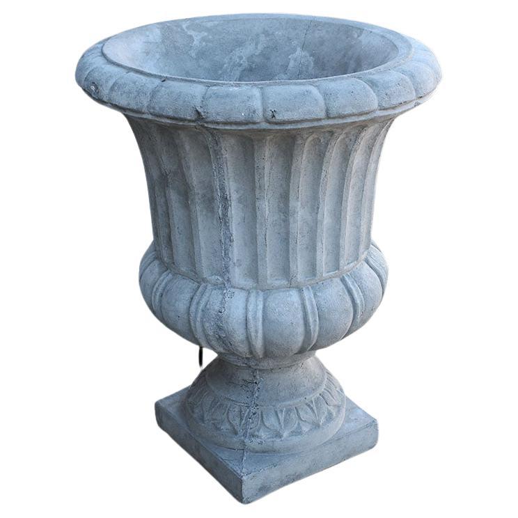 A set of two large rustic French concrete garden planters. This pair of garden planters sit upon square concrete bases. The fluted sides feature scalloped stylized decorations. This pair will be fabulous flanking a front door, or on a patio. We also