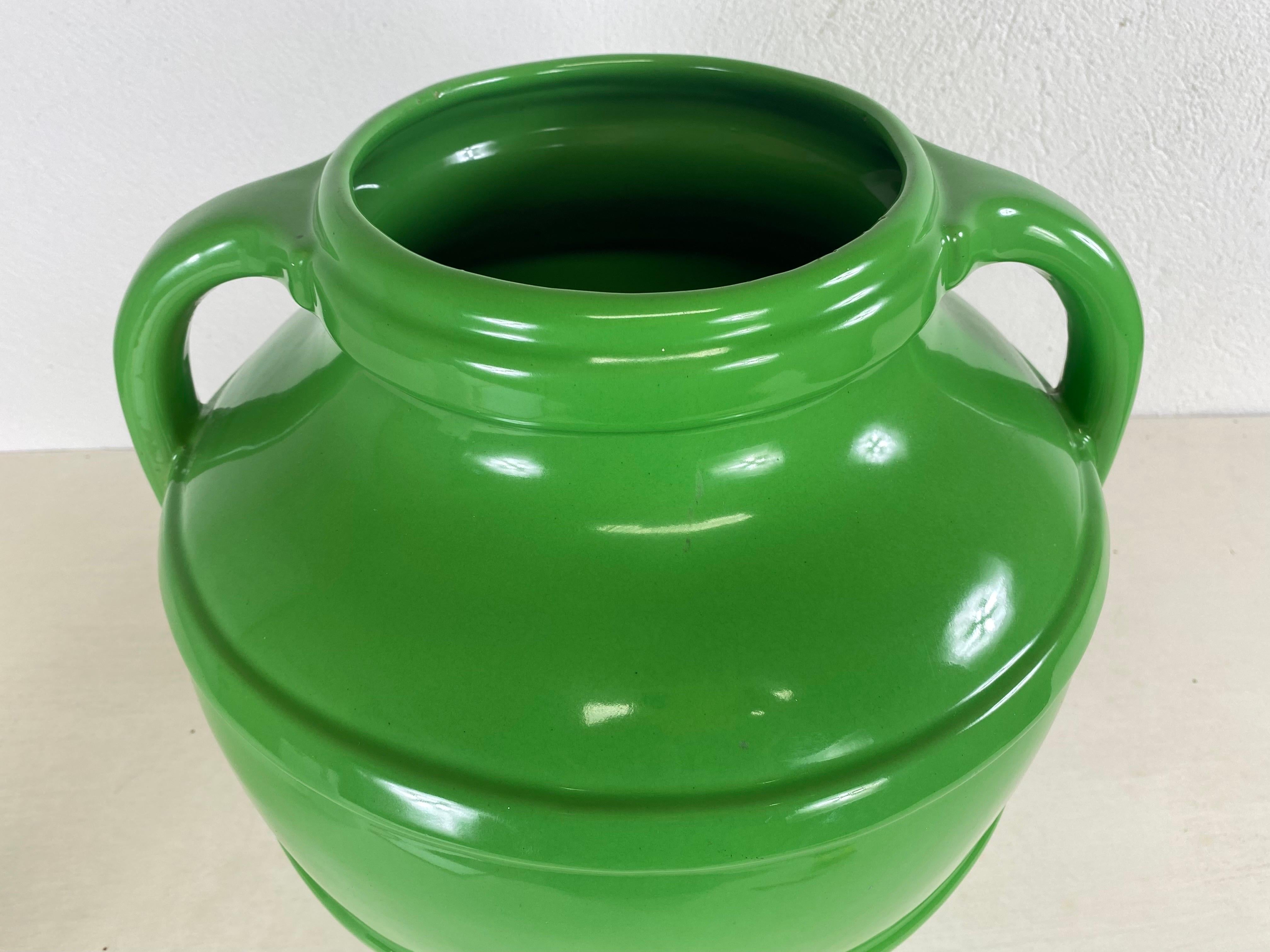 This is a vintage oversized, apple green pottery vase. This vase has two handles on either side and ribbed details around the surface. This dynamic Art Deco vase is in a brilliant apple green color. This deco style vase is American circa 1950.