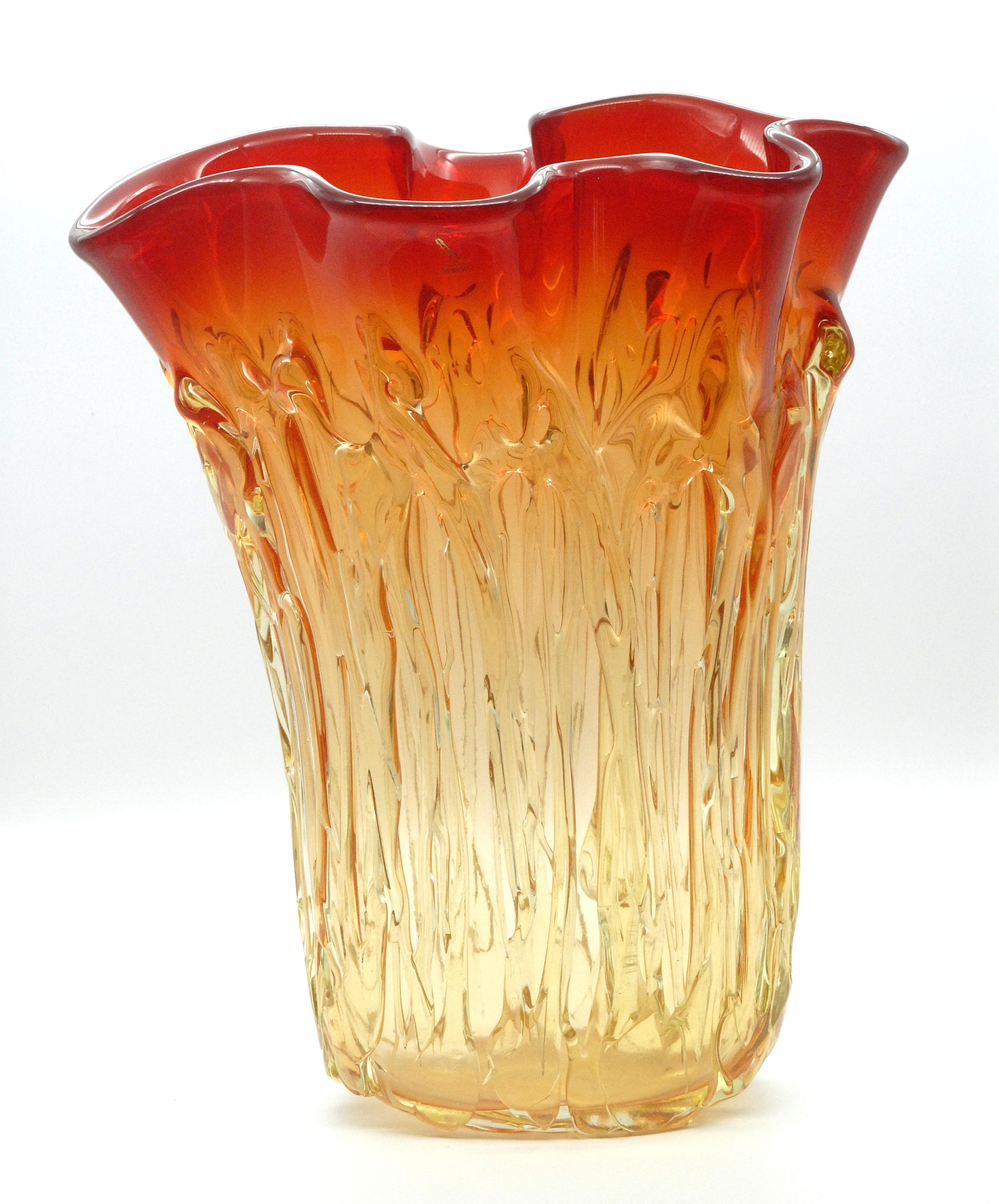 A very large and heavy glass vase by Enrico Cammozza, signed on the base and with a label on the outside of the body. Freeform shaped neck rim graduating from deep orange down to a very pale yellow at the base. Lovely moulding on the body of grass