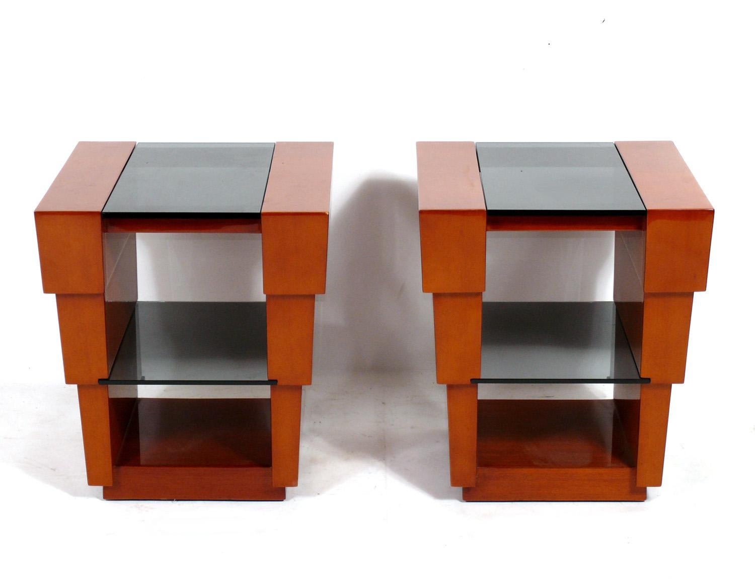Pair of elegant stepped design tables, designed by Enrique Garcel, Colombia, circa 1980s. They are a versatile size and can be used as end or side tables, or as night stands. They are constructed of tropical woods and smoked glass.