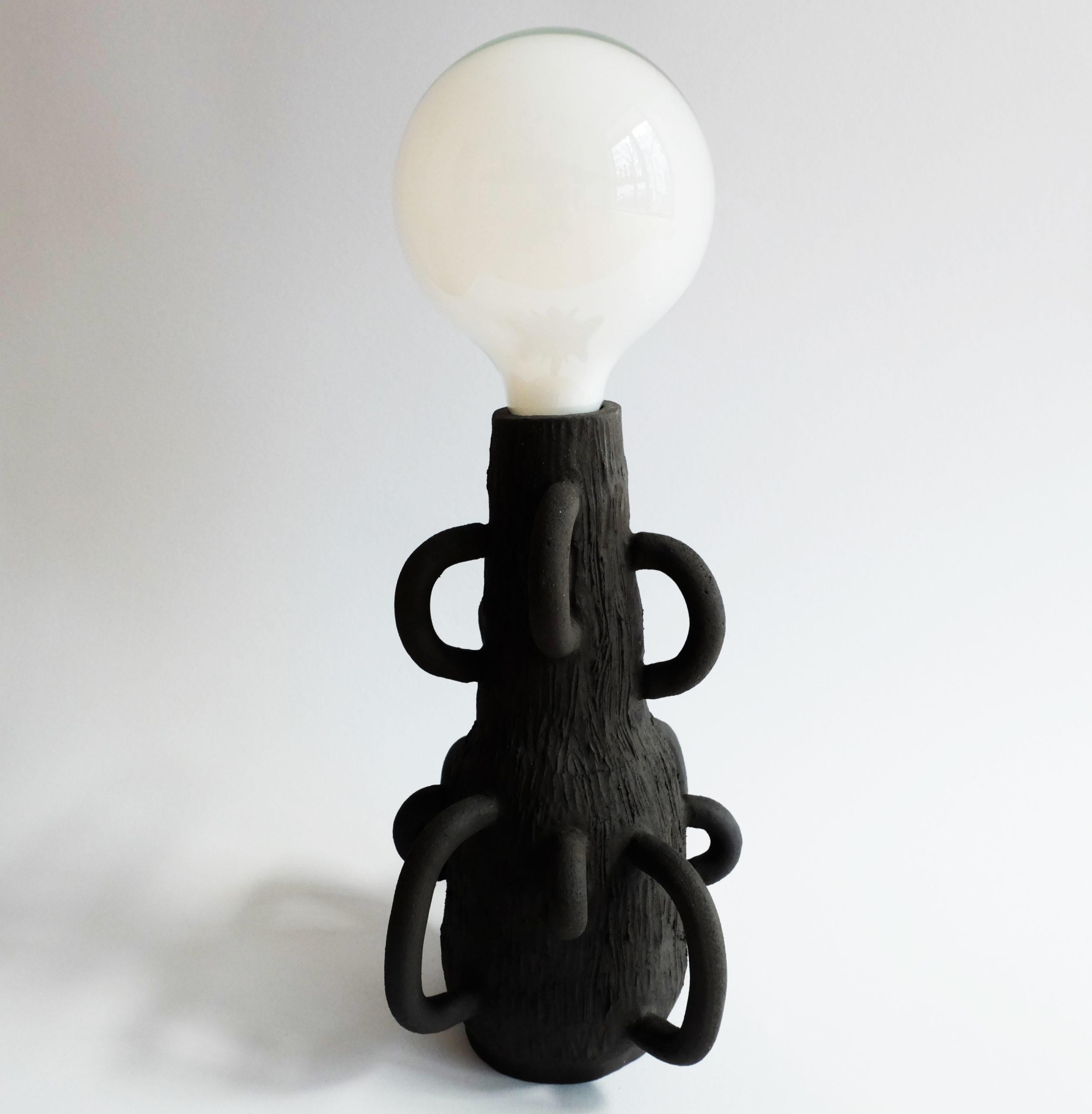 Enssi Table Lamp by Ia Kutateladze
One Of A Kind.
Dimensions: W 19 x H 30 cm.
Materials: Ceramic.

Each piece is one of a kind, due to its free hand-building process. Different color variations available: raw black clay, raw white clay and raw red