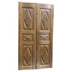 Puerta de entrada en nogal, con dos batientes y paneles tallados, Italia