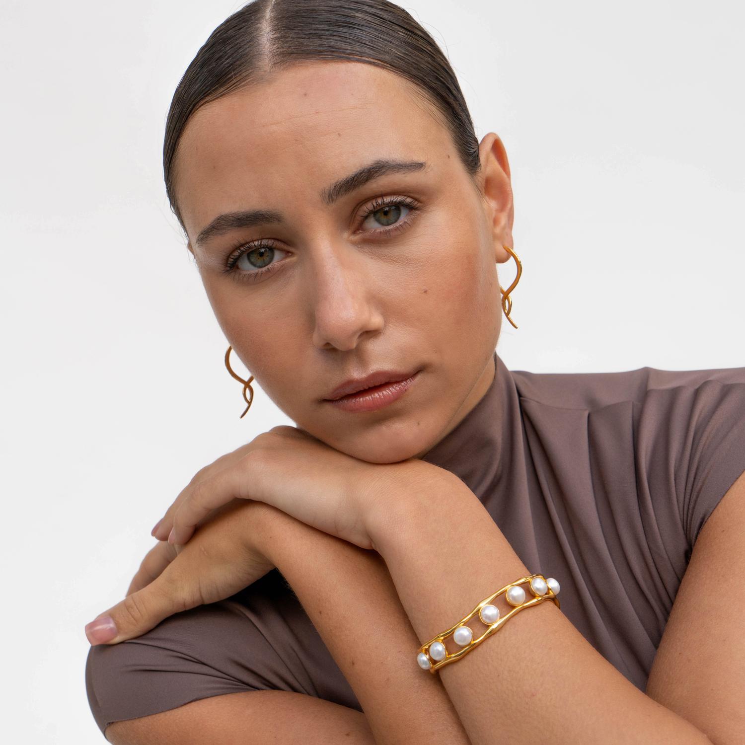 These sculptural hinged hoops have a unique double twist and are a mirror pair, adding fascination to their classic design. Made of sterling silver with a radiant yellow gold vermeil finish, the earrings have our signature hammered texture. Wear