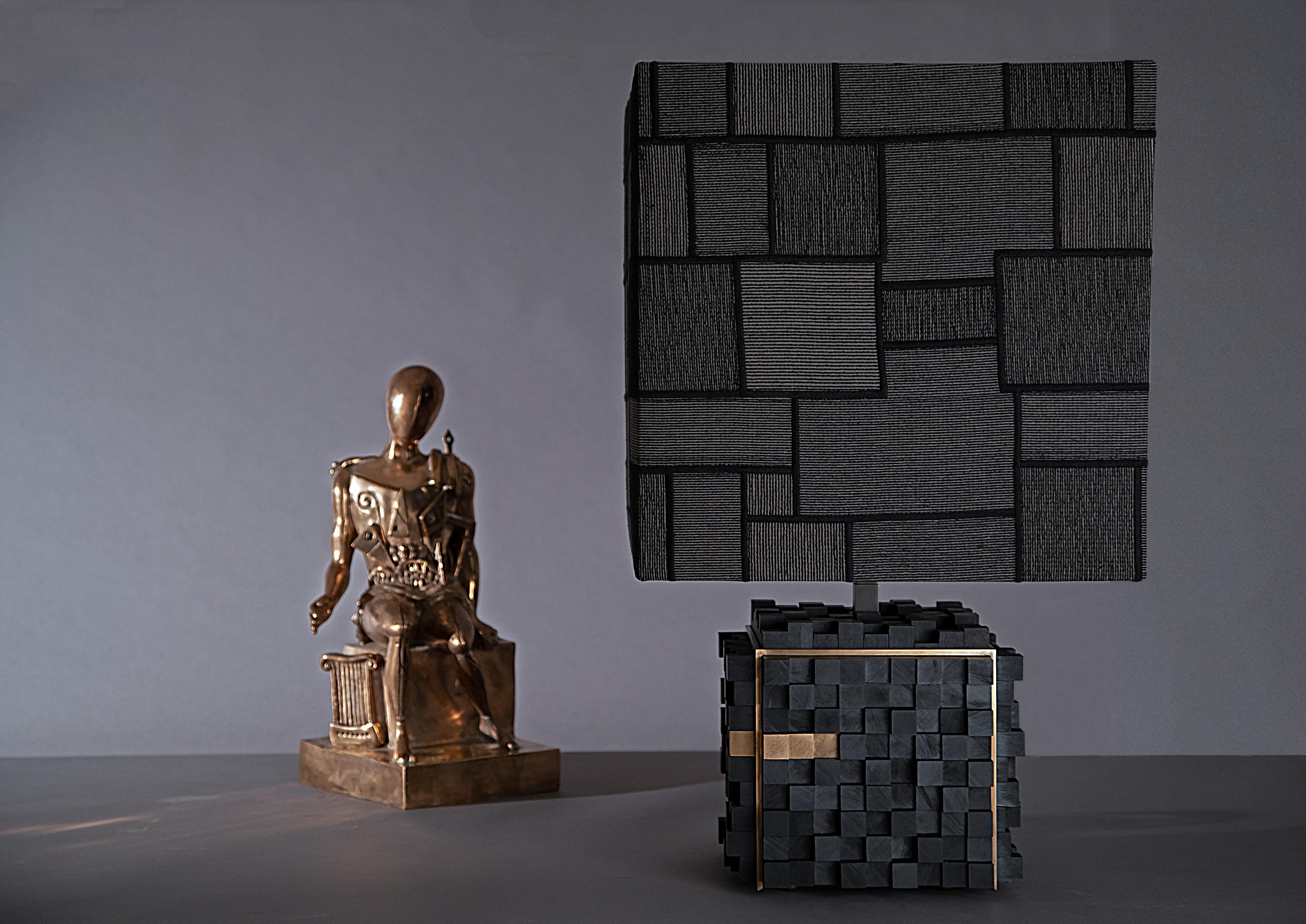 Lámpara de mesa Envie de Arch Plus Ultra
Dimensiones: An 42 x Pr 42 x Al 70 cm.
Materiales: Madera de ébano, Latón, Jacquard de trevira.

Inspirados en el arte del mosaico bizantino, pequeños cubos irregulares de madera maciza de ébano se ensamblan
