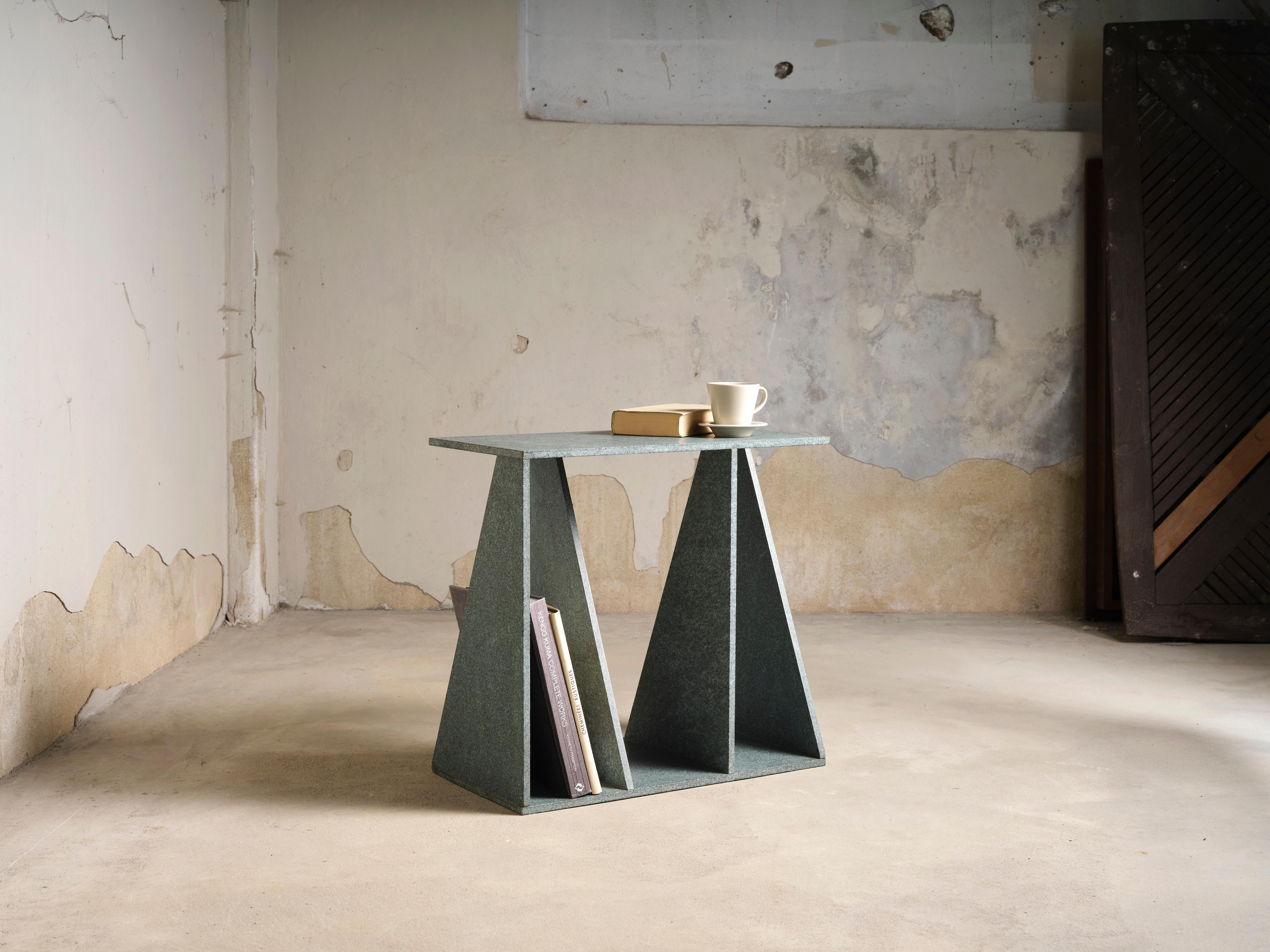 A study in geometric transformation and material integrity, Envo Table is a sculptural piece that redefines the concept of a side table. Carved from volcanic diabase stone, its deep green hue and textured surface evoke a raw yet refined