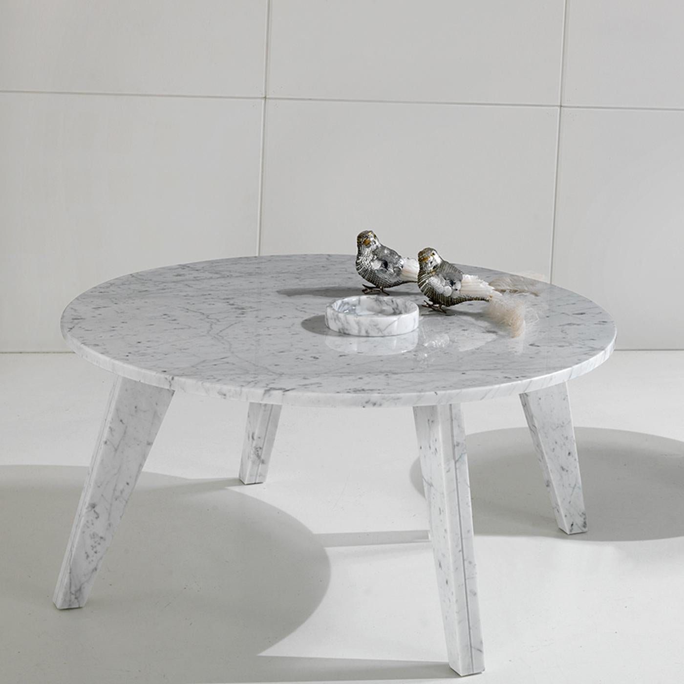 The luxury of white Carrara marble enhances the allure of this stunning coffee table. The gray veins dancing over the white background of the precious stone, quarried in the city of Carrara in Tuscany, make the tapered legs and the round top for an
