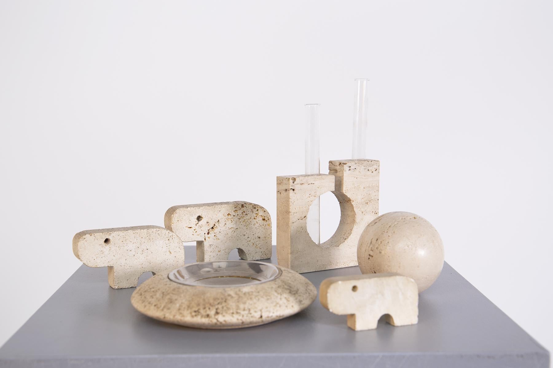 Decorative set by Enzo Mari made of travertine from the 1970s.
The set consists of three animal-shaped sculptures, an ashtray made of travertine and steel, a flower holder also made of travertine with two glass ampoules for placing two flowers