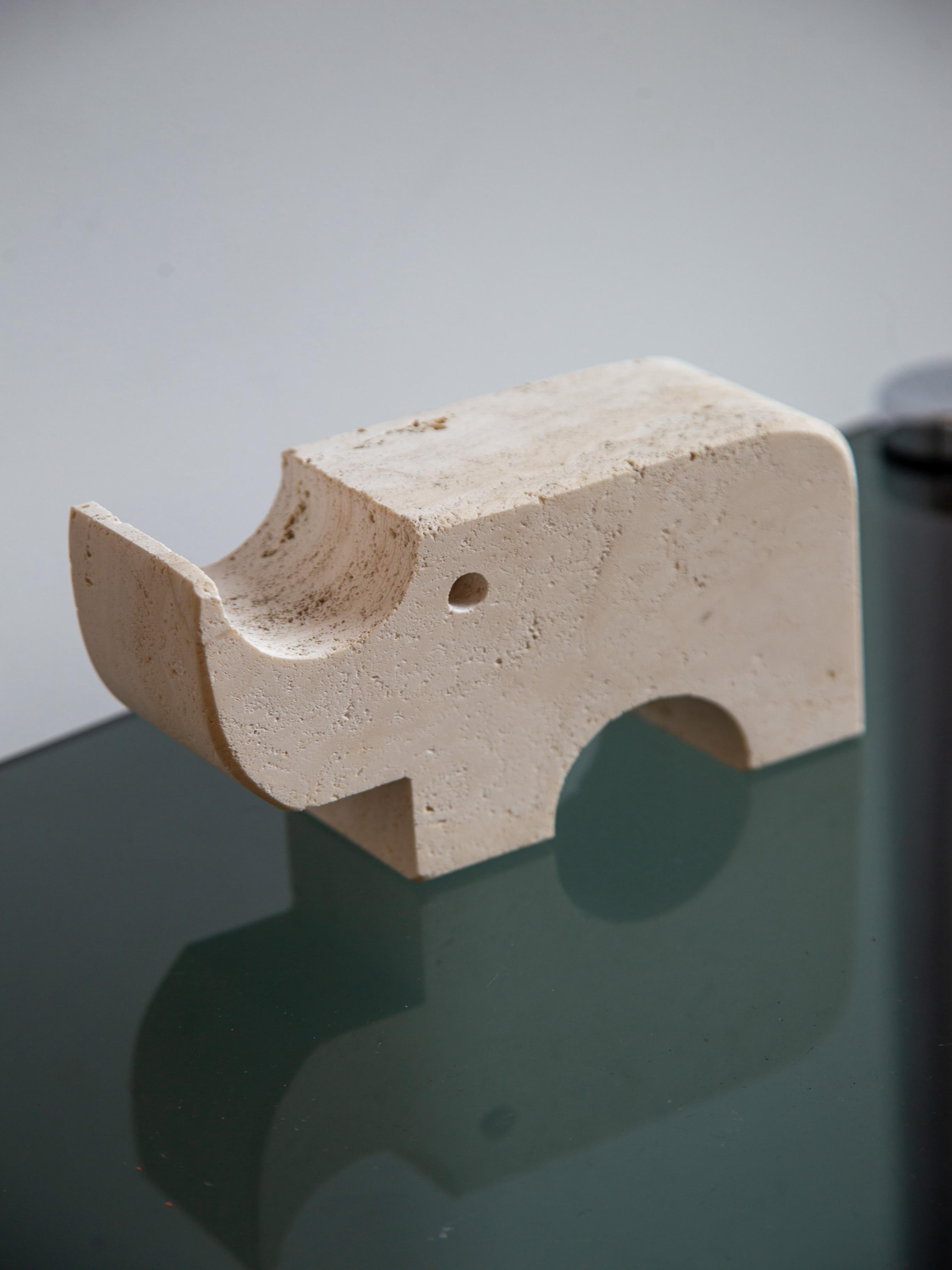 Un'affascinante e iconica scultura disegnata da Enzo Mari per i Fratelli Mannelli negli anni '70, scolpita a mano in travertino massiccio. Questo rinoceronte minimalista mostra il caratteristico mix di astrazione giocosa e linee geometriche pulite