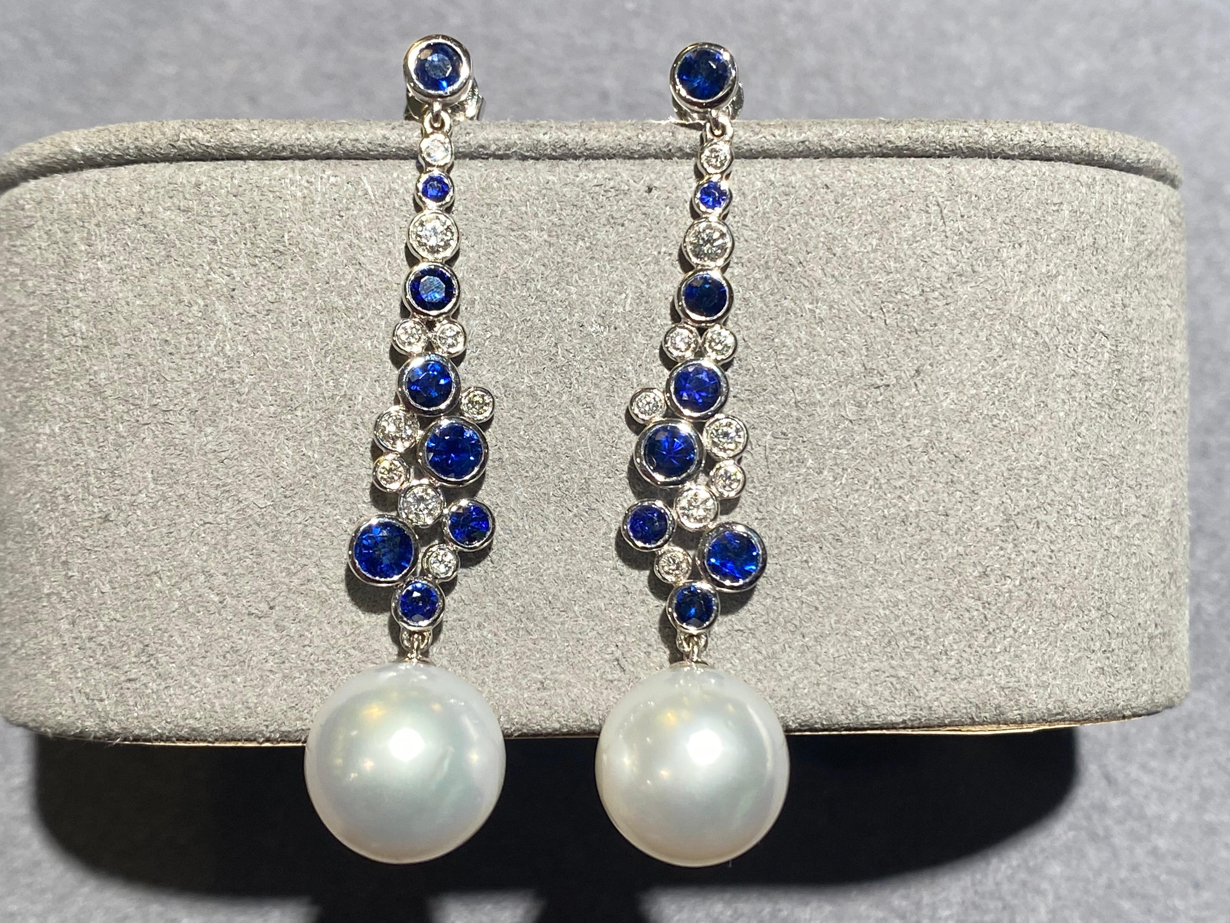 A pair of blue sapphire and diamond earrings in 18k white gold. The earrings is consists of a blue sapphire stud and it is then connected to the white Australian south sea pearl via 