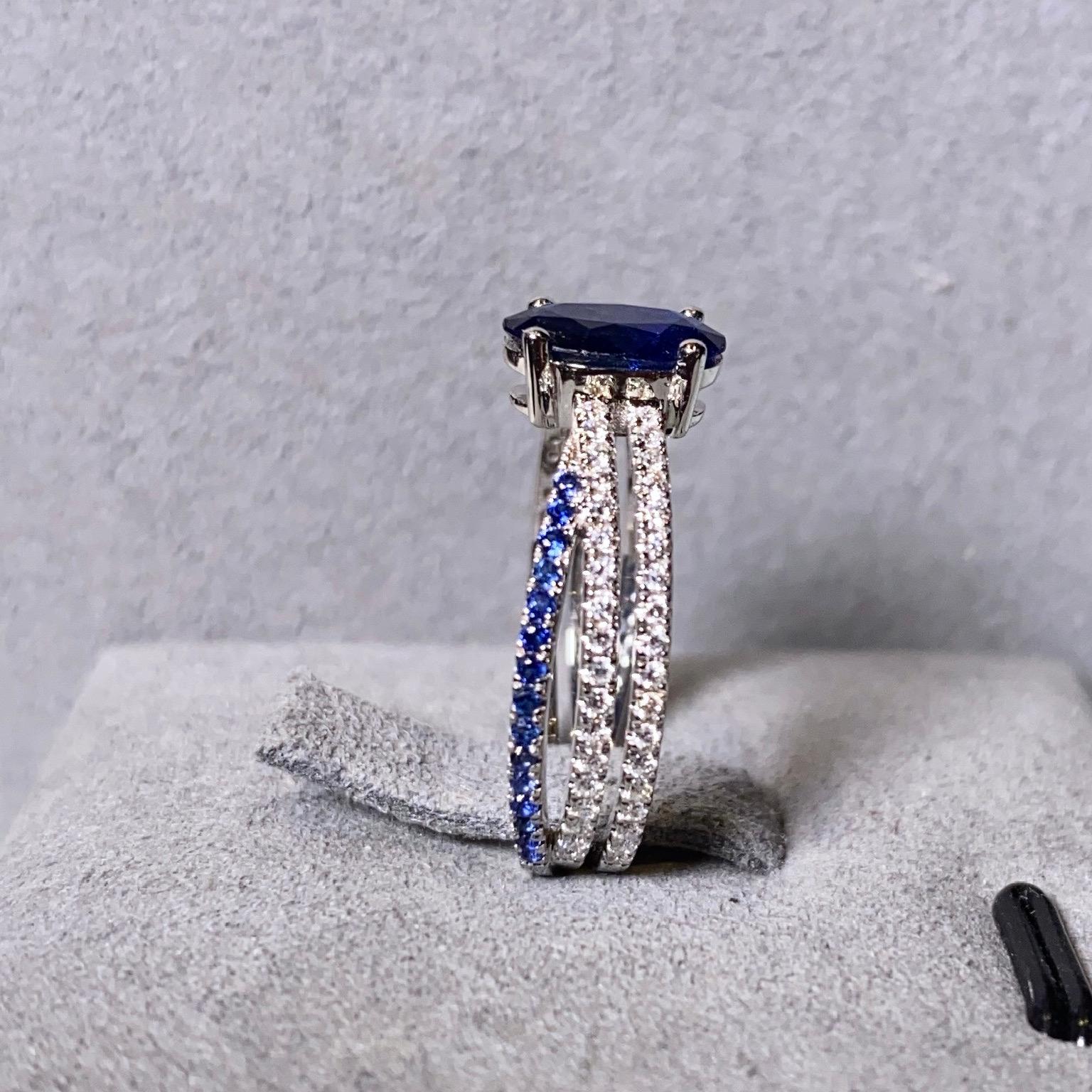 Blue Sapphire and Diamond Ring in 18k White Gold. The main sapphire is secured by 4 white gold claws and the band of the ring is made up of 3 individual pave bands. The 2 diamond pave bends are parallel to each other while the sapphire pave bend