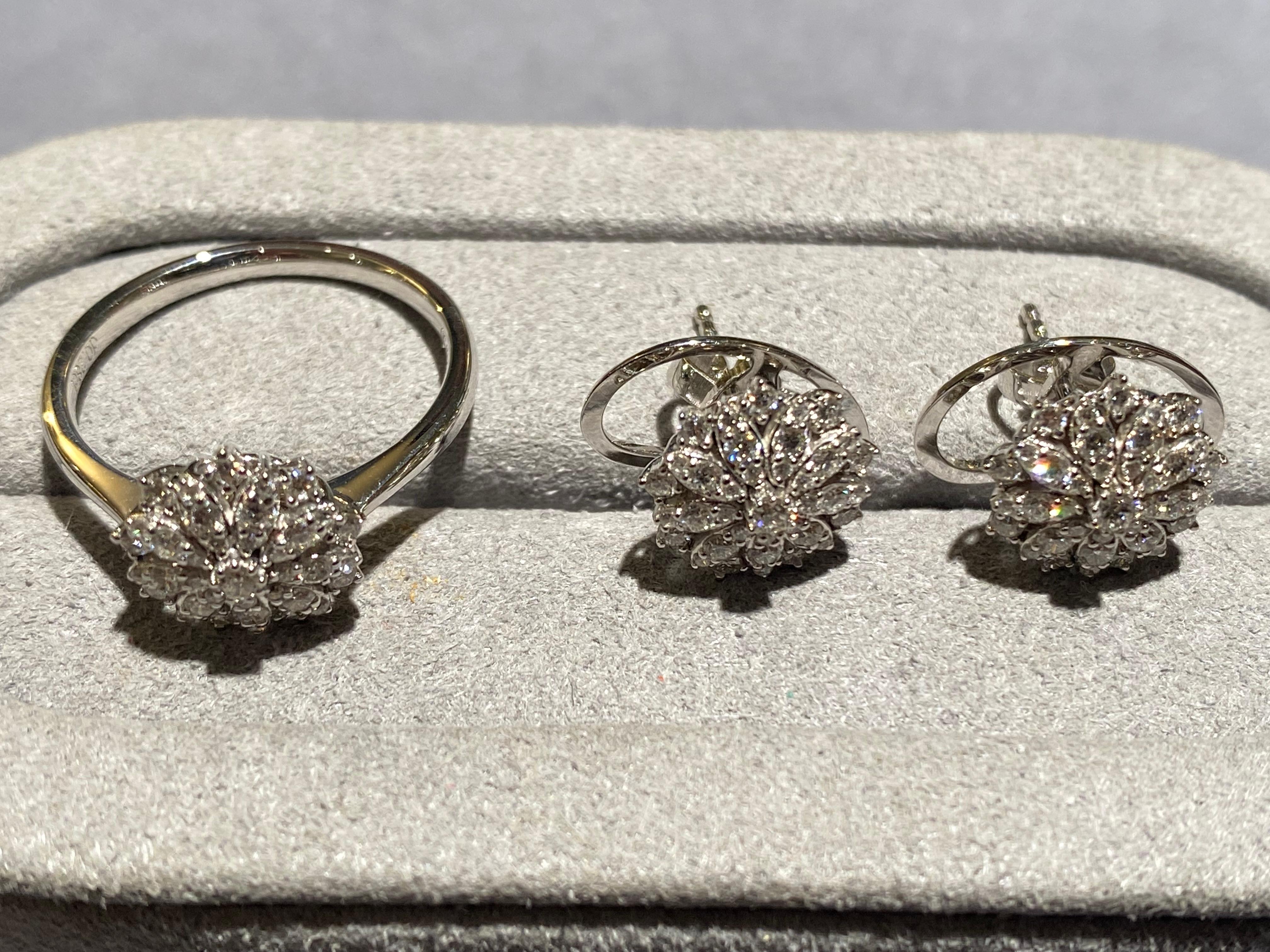 Una parure di orecchini e anelli con diamanti a motivo floreale in oro bianco 18 carati. Al centro del motivo floreale c'è un diamante rotondo taglio brillante. Intorno al diamante ci sono molti petali allungati e i petali sono incastonati con micro