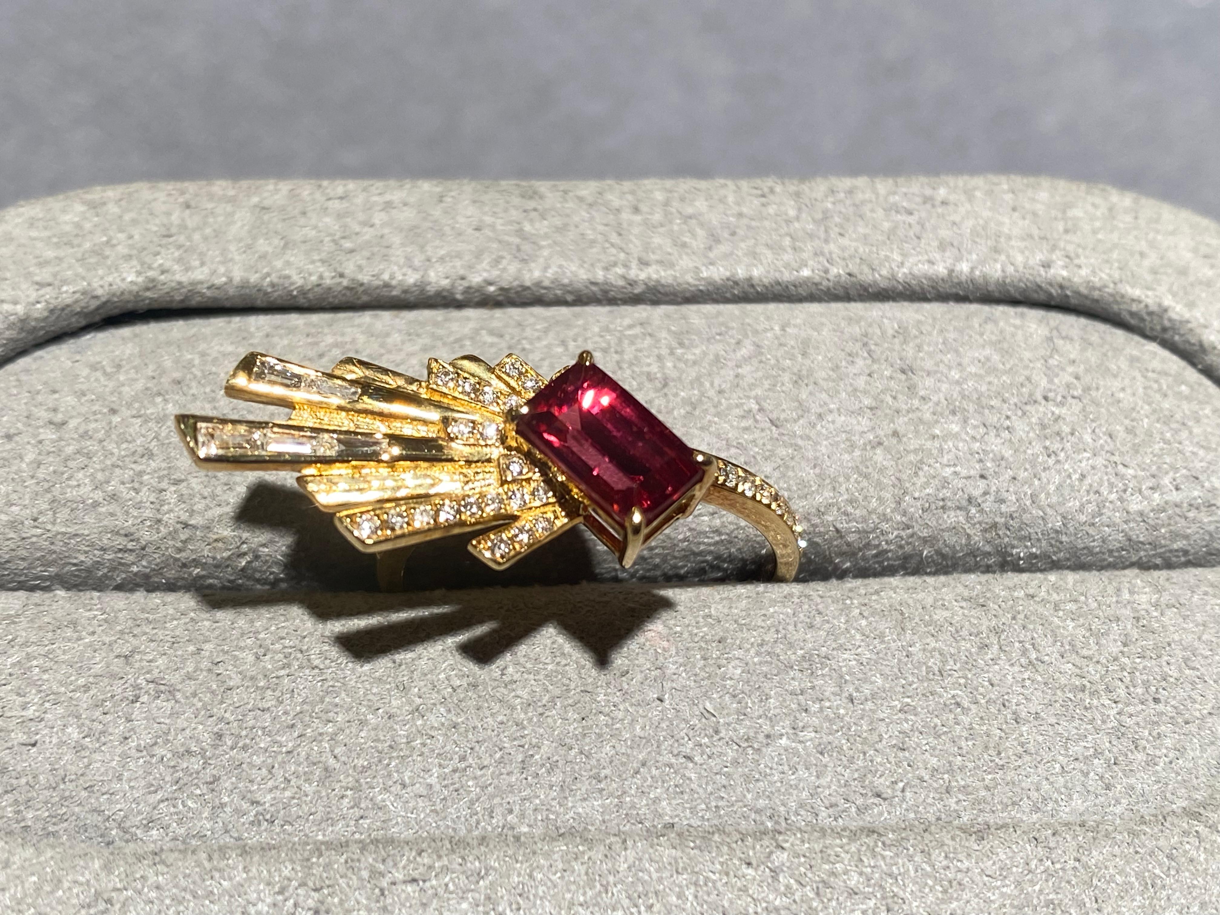 A red spinel and diamond ring in 18k yellow gold. The rectangle spinel is set at an angle  to the ring band. There are fireworks-like structure coming out from the tourmaline and some of the structures are set with diamonds. This is a very simple