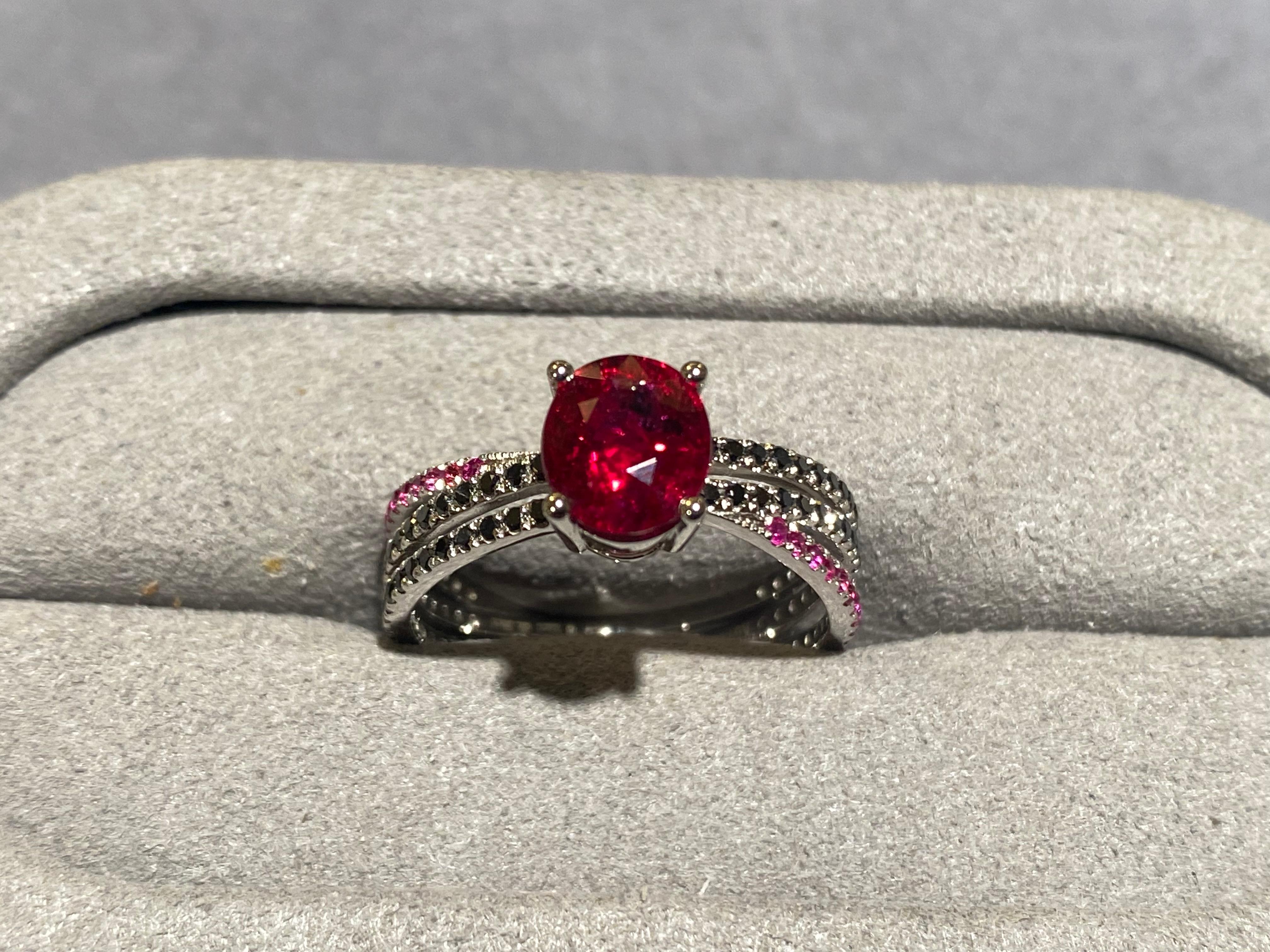 Ruby and black diamond ring in 18k white gold. The main ruby is secured by 4 white gold claws and the band of the ring is made up of 3 individual pave bands. The 2 black diamond pave bends are parallel to each other while the ruby pave bend