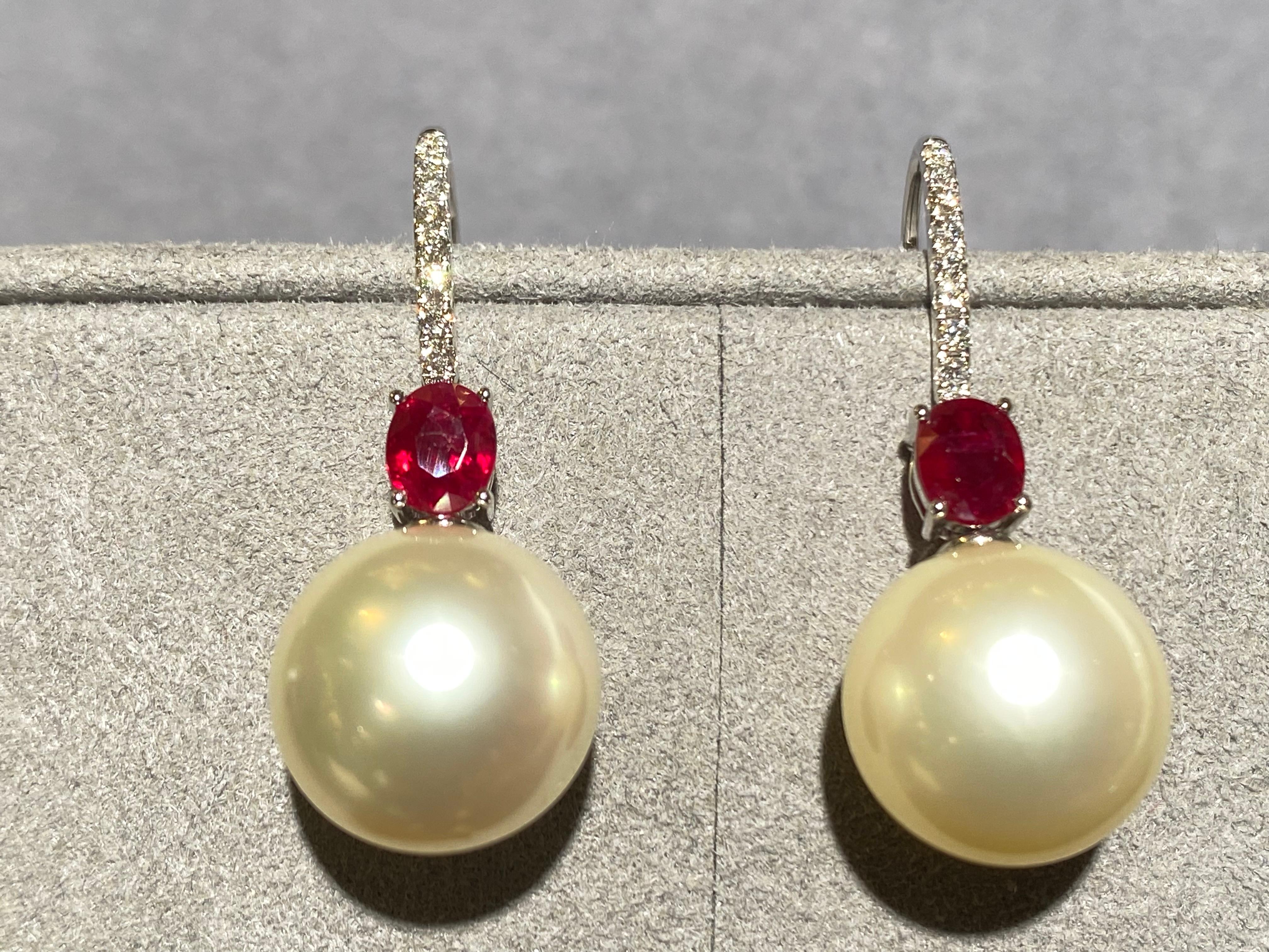 A Pair of Ruby, Champagne Colour South Sea Pearl and Diamond Earrings in 18k White Gold. It is a simple drop design with the pearls hanging underneath the ruby, it is then connected to the shepherd hook. Diamonds are set on the front of the shepherd
