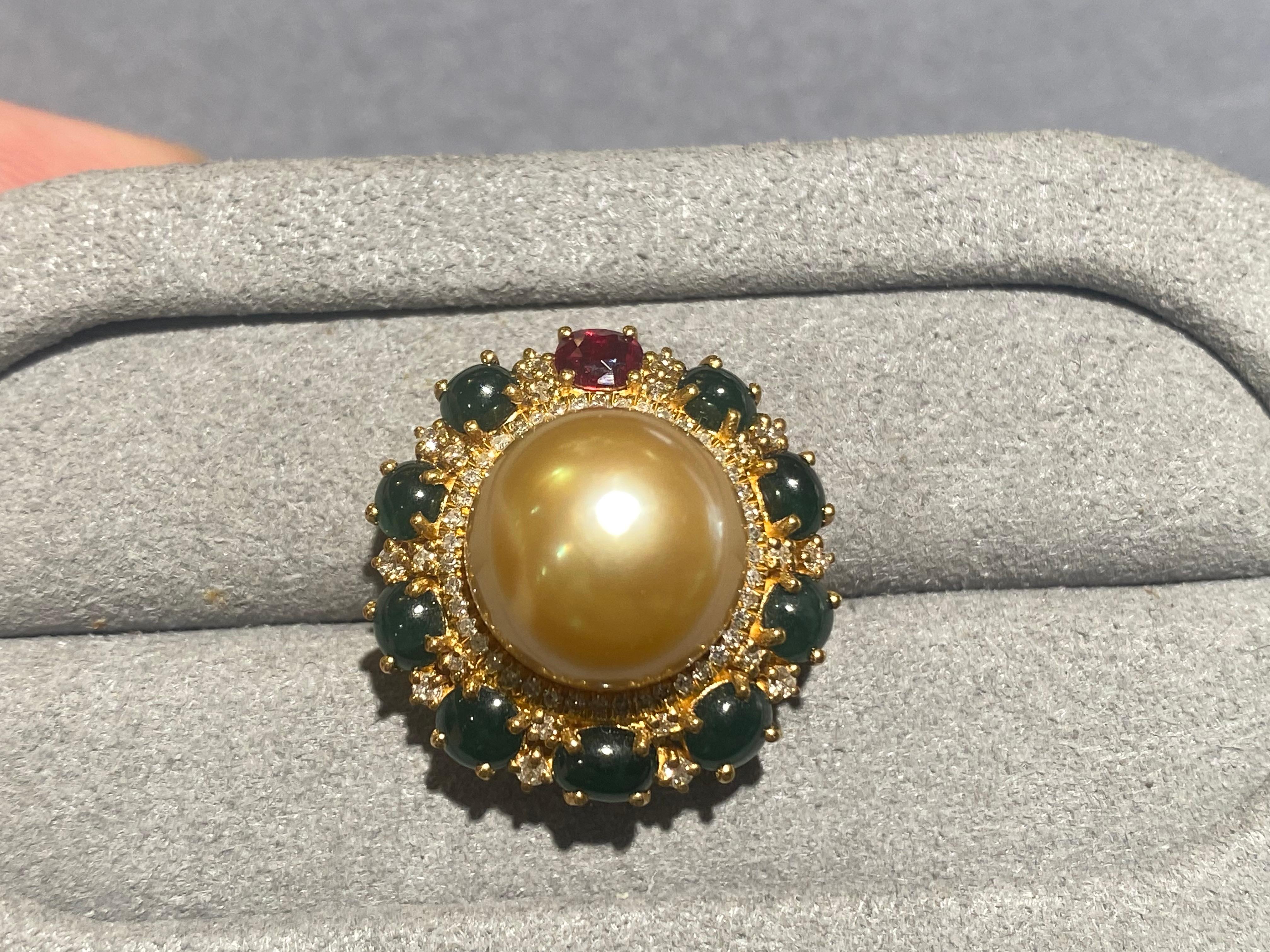 A 11.6 mm deep golden south sea pearl is set in the middle of a floral motif pendant in 18k yellow gold. The outer layer of the pendant is set with a vivid red ruby and 9 type A green jadeite. There are 2 diamonds set between each green Jadeite and