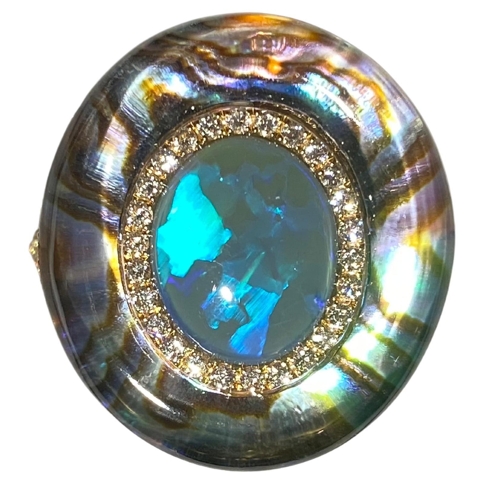 A 2.27 ct Solid Opal, Abalone Shell, Crystal and Diamond in 18k Yellow Gold. The solid opal is surrounded by a circle of diamond pave, on the outer circle is where the abalone shell is. The abalone shell is cover by thick crystal  giving the ring a