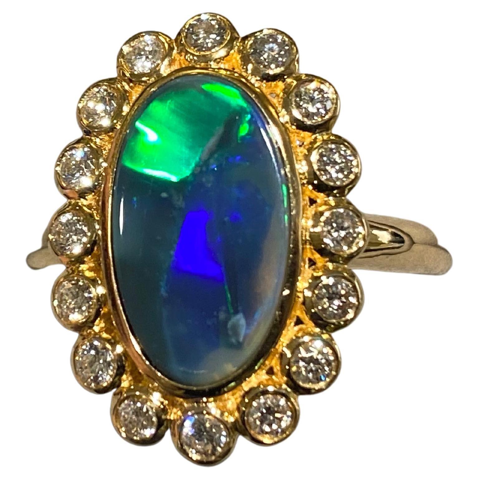 A  1.74 ct solid opal and diamond ring in 18k yellow gold. The opal is surrounded by a circle of diamond pave. This is the vintage cluster ring design and it is an old time favorite of many. The main colour of the opal is green with a few patches of