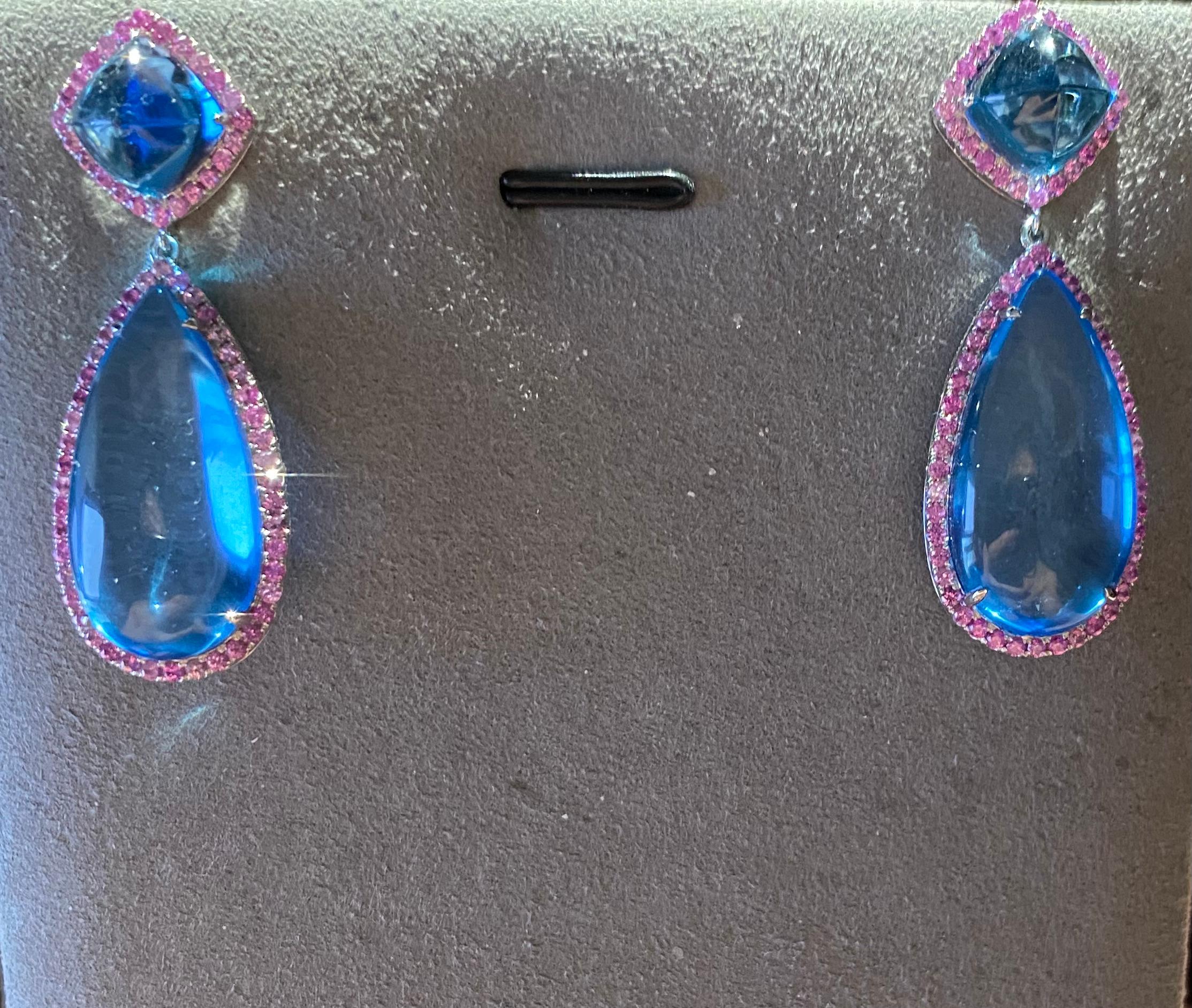 This is a Pair of Dangle Earring consists of 35ct of Blue Topaz. On top end, there are 2 sugarloaf Topaz surrounded by pink sapphire. They were followed by 2 massive raindrop Topaz Cabochon. The Topaz cabochon is also surrounded by pink sapphire