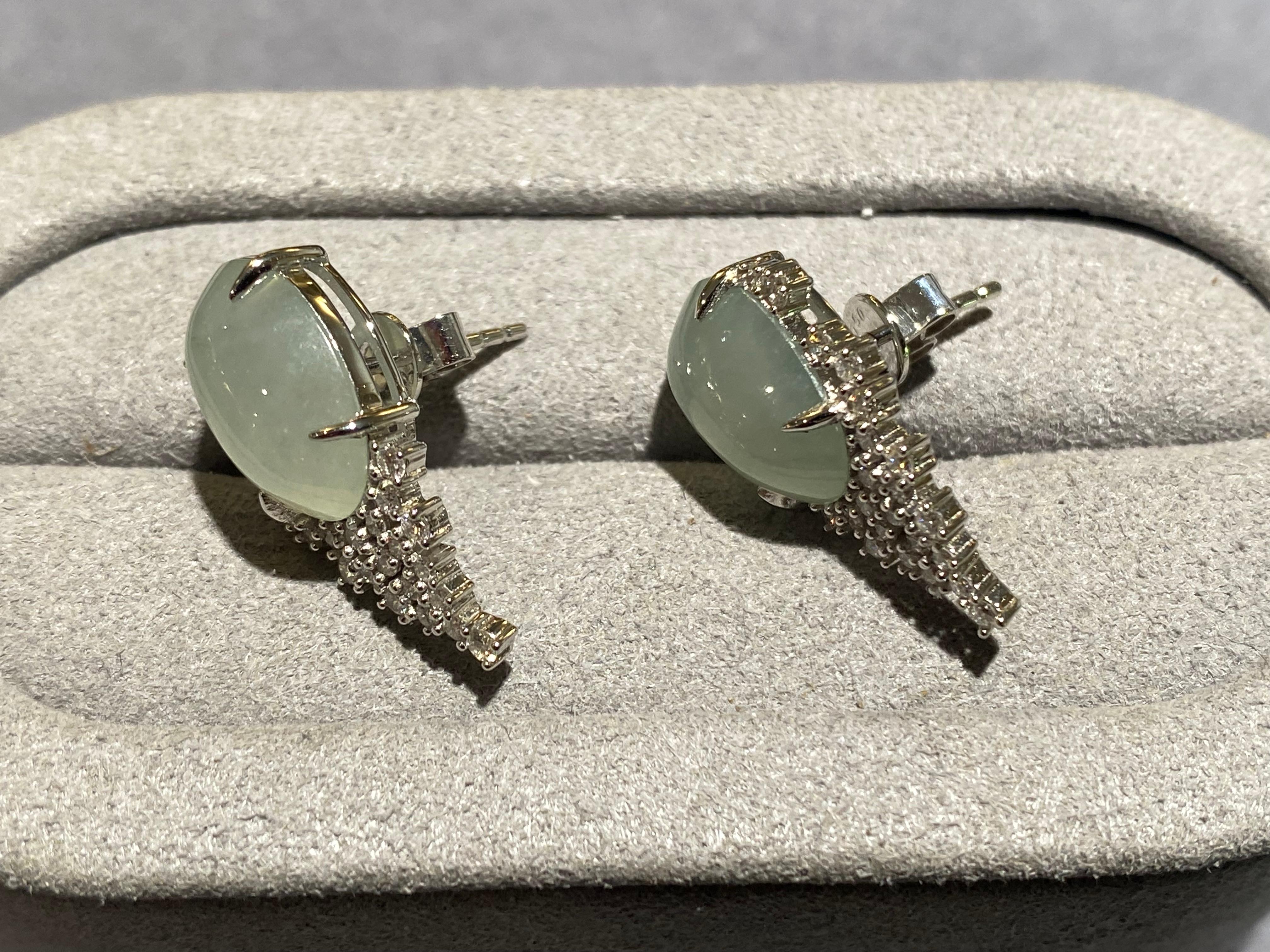 A pair of type A green jadeite and diamond earrings in 18k white gold. The oval cabochon jadeite is secured by 4 claws and at the bottom of the jadeite there is a drape of micro diamond pave. It started off with many and slowly decrease in number as