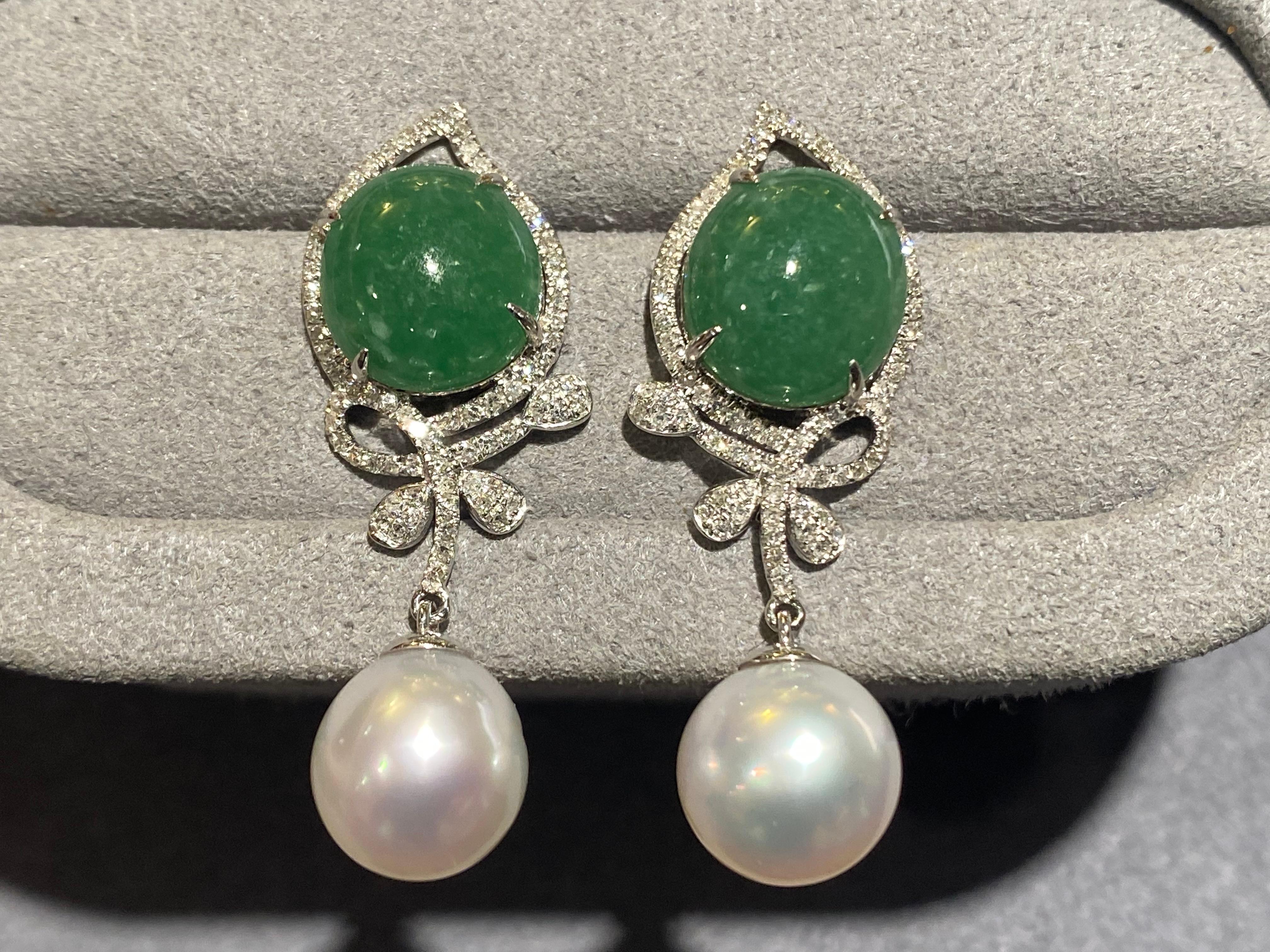 A Pair of Type A green jadeite, Australian White South Sea Pearl and Diamond Earrings in 18k White Gold. The type A green jadeite is set within a rain-drop shape diamond pave and is secured by 4 claws. The butterfly-like ribbon pattern is set with