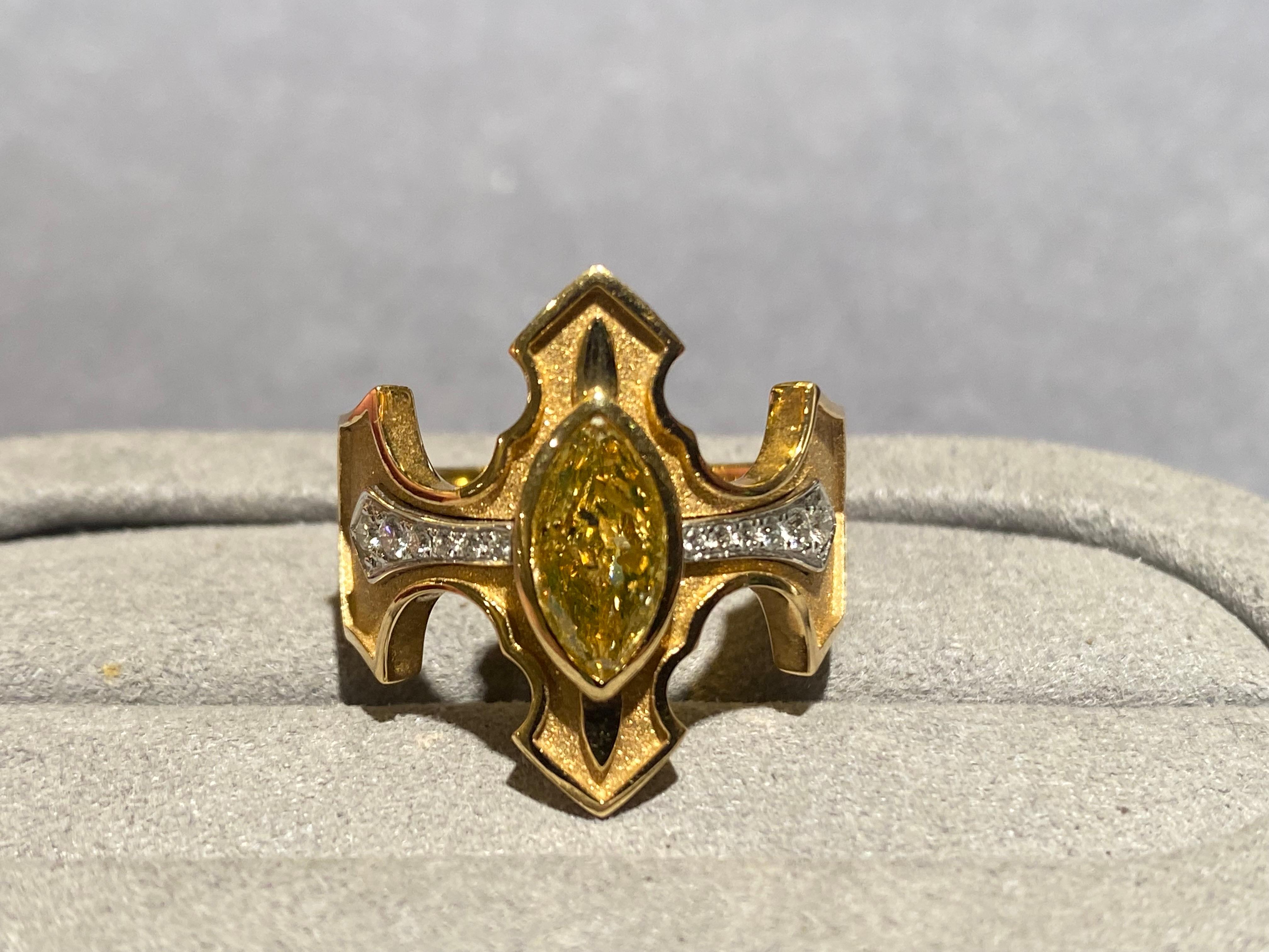 A marquise yellow diamond and diamond ring in 18k yellow gold. The yellow diamond is set in the middle of a crown like motif. The are graduating white diamond set beside the yellow diamond running along the horizontal axis of the ring. The ring
