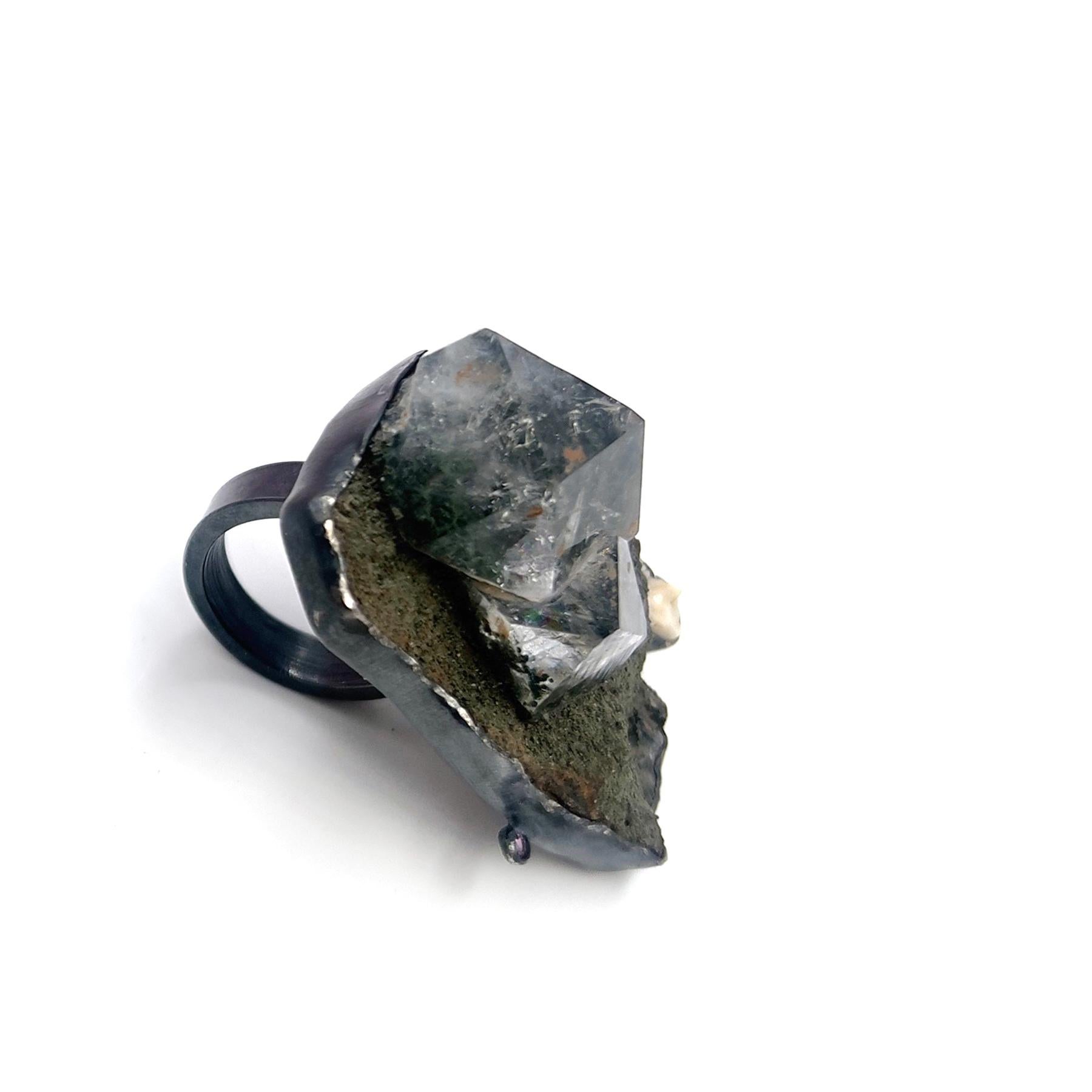 The Epidosis ring is a captivating fusion of nature's finest elements. Hand-crafted with meticulous attention to detail, the top face of the ring boasts a harmonious arrangement of Epidote, Racoon Tooth, Tourmaline, and Silver—a symphony of colors