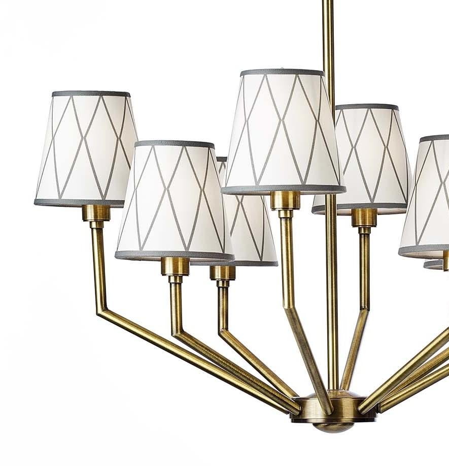 Part of the Epoque collection, this modern chandelier is extremely versatile and eye-catching. Marked by a stylized silhouette, the tubular structure has an antique brass finish with eight angled arms departing from the circular base and extending