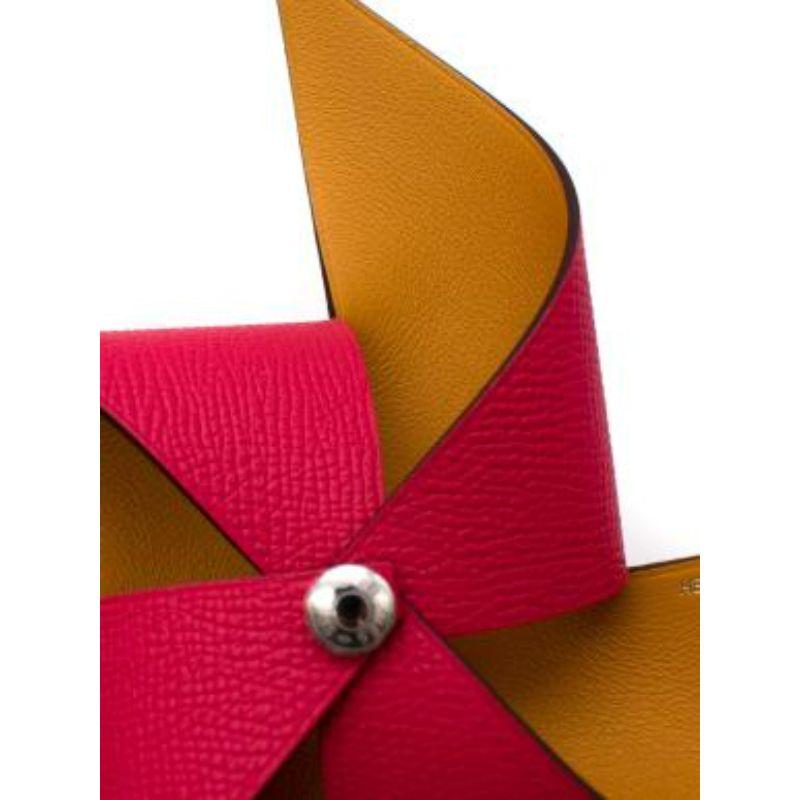 Hermes Epsom Leather Petit H Pinwheel
 
 
 
 -Hermès-engraved silver center pin
 
 -Pink & Yellow leather blades 
 
 -Sitting on a long wooden stick 
 
 -Pointed edges 
 
 
 
 Material: 
 
 
 
 Leather and Hackberry Wood
 
 
 
 Made in France 
 
 
