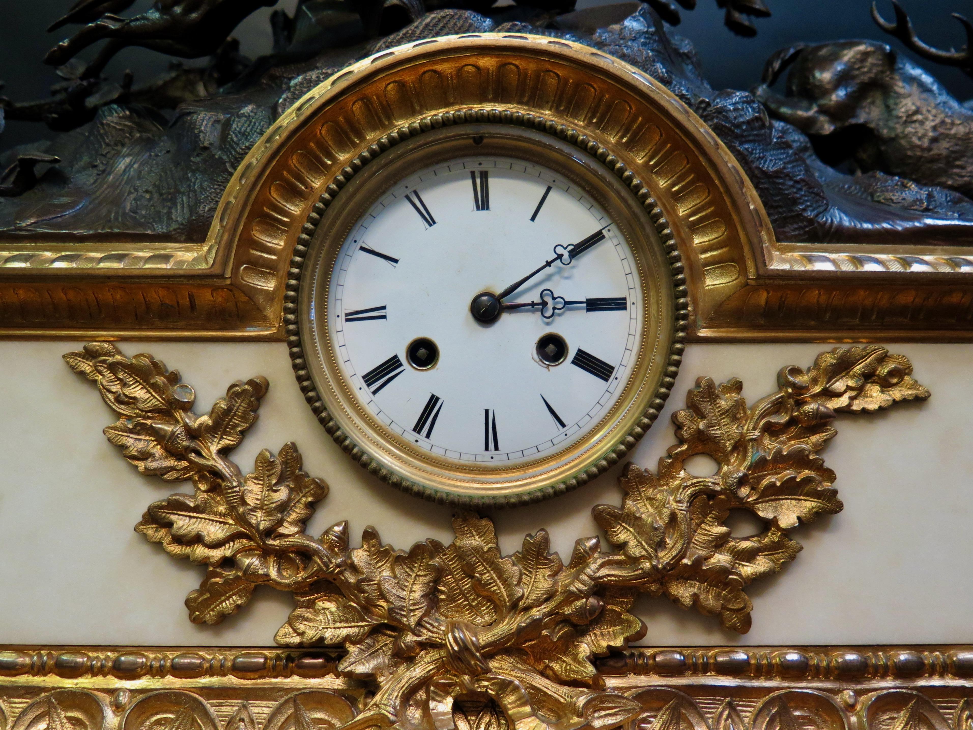 This early 19th century timepiece includes a patinated bronze sculpture of the thrill of the hunt, mounted upon a huge decorative marble & bronze clock case. The sculpted bronze is of a country gentleman sounding his horn while mounted on a