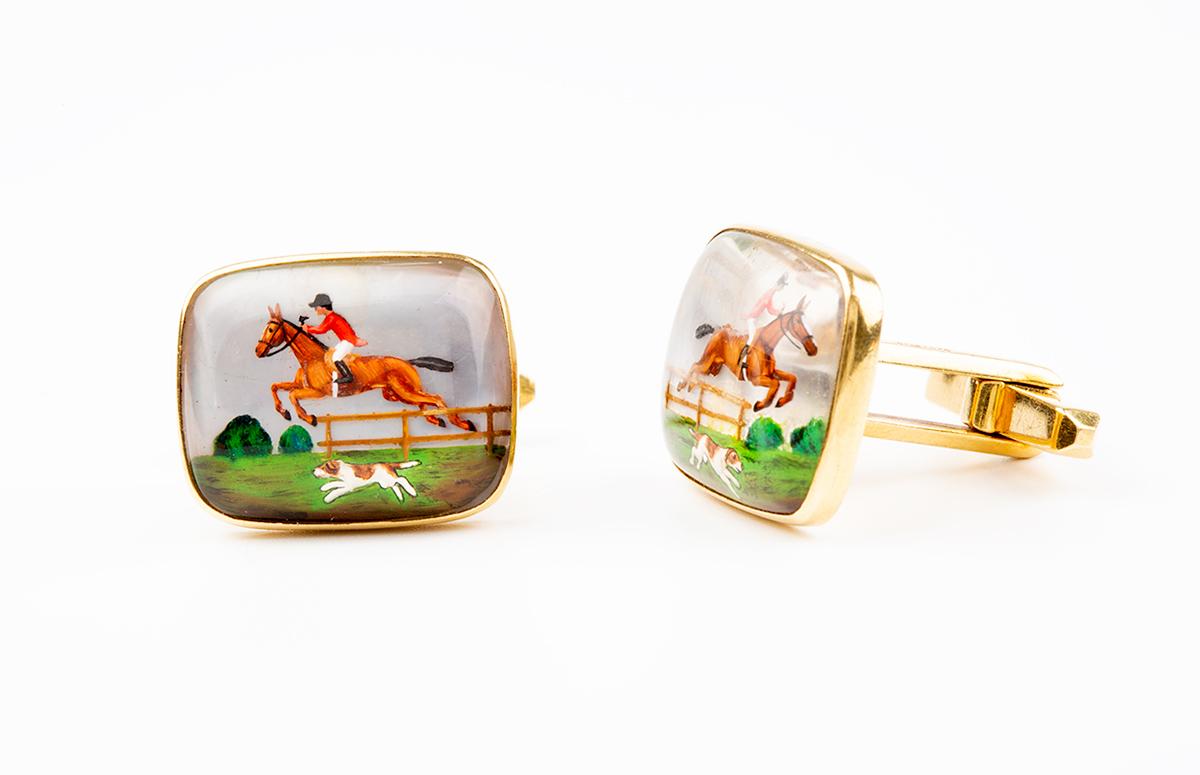 Equestrian cufflinks of a painted hunting scene depicting a huntsman and his horse jumping a fence with a hound in the foreground. These single sided crystal cufflinks have a mother of pearl background all mounted in 18 carat yellow gold. The