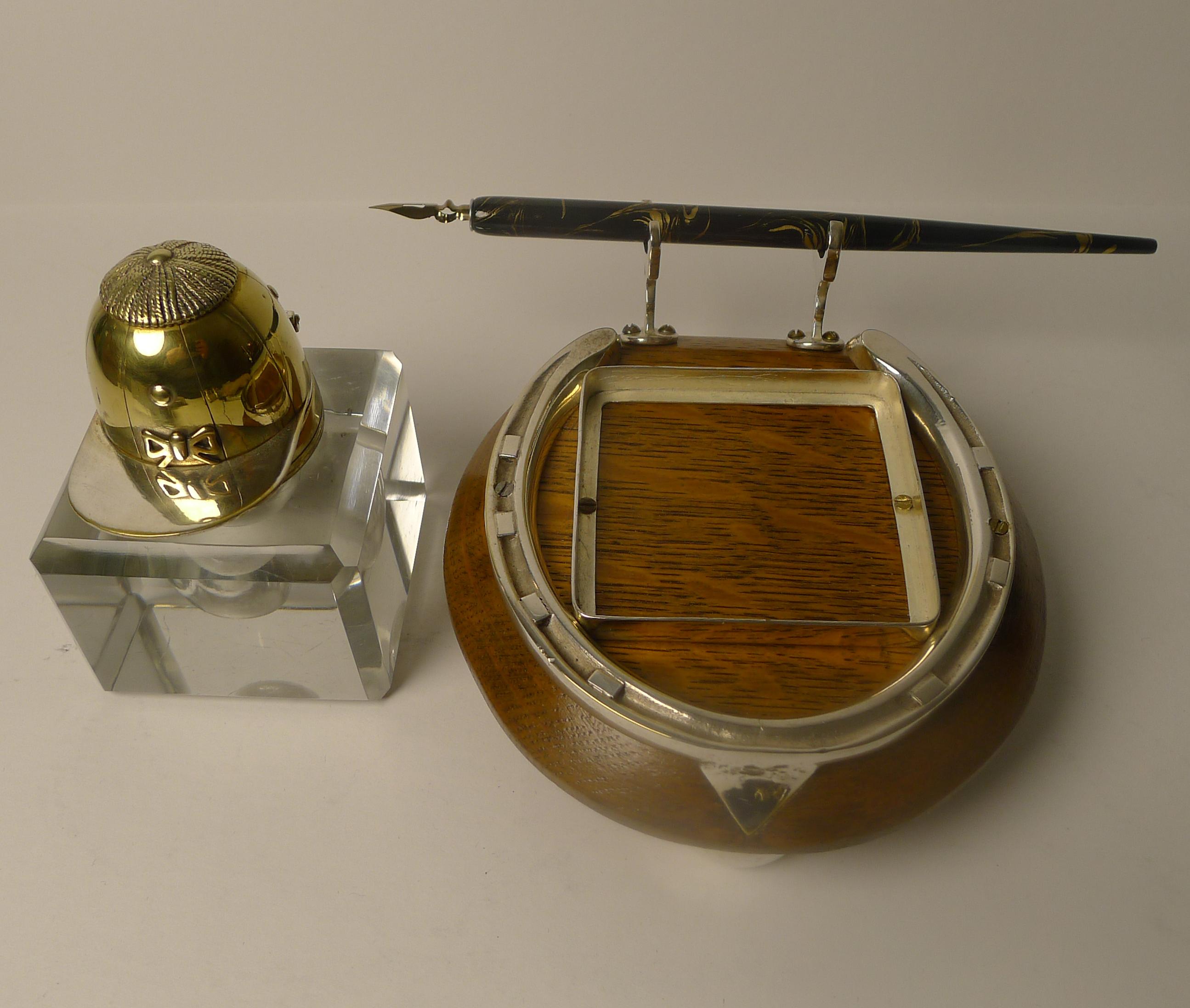 A handsome Horseshoe shaped inkstand, the base made from solid English Oak mounted with a silver plated horseshoe and a square gallery to secure the glass inkwell.

The glass inkwell is topped with a hinged brass lid in the form of a Jockey's cap
