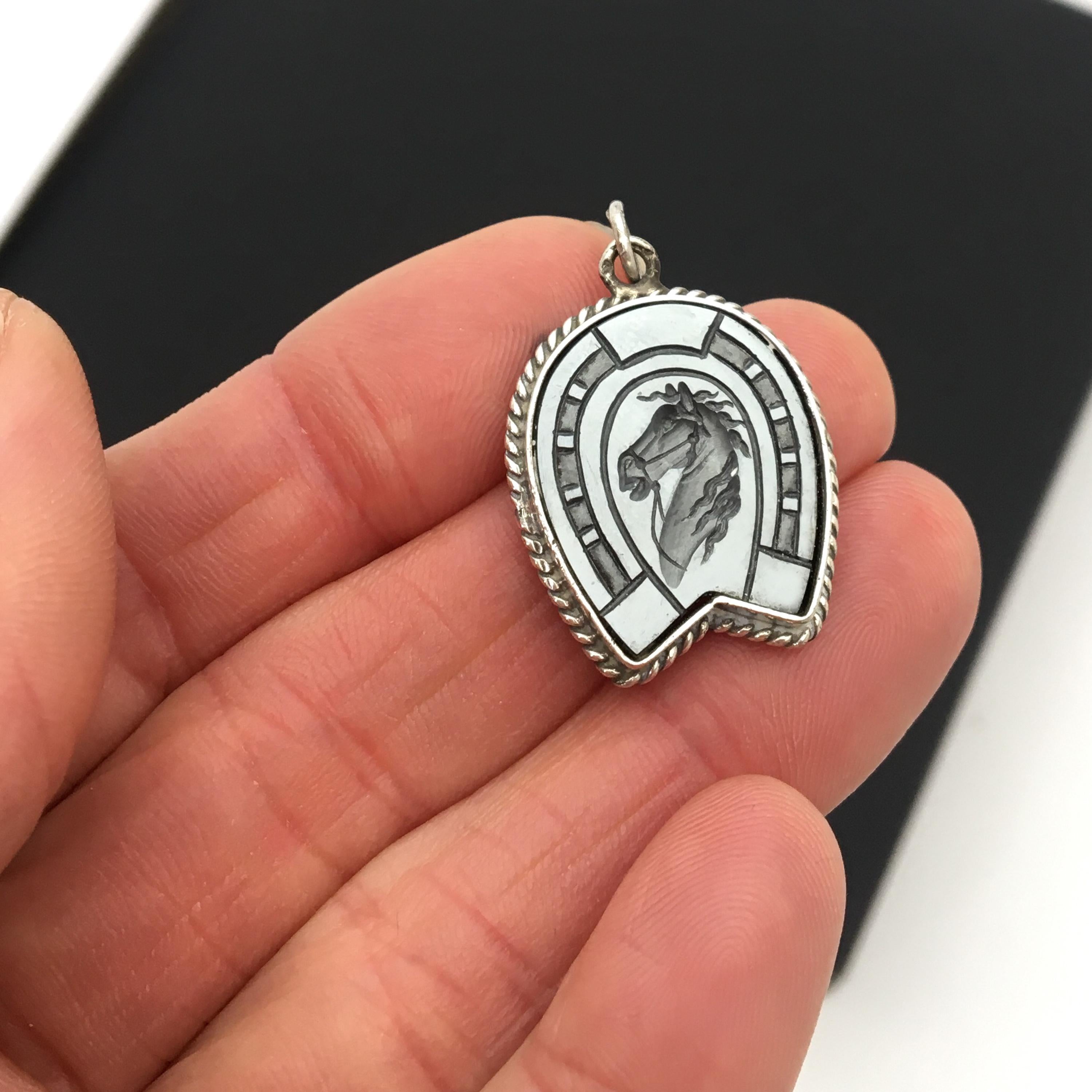 An equestrian vintage silver charm pendant in the shape of a horse shoe with an intaglio of a horse head. The stallion's head is beautifully detailed with his wild mane and ready for action. 

The charm would be great worn alone on a necklace charm,