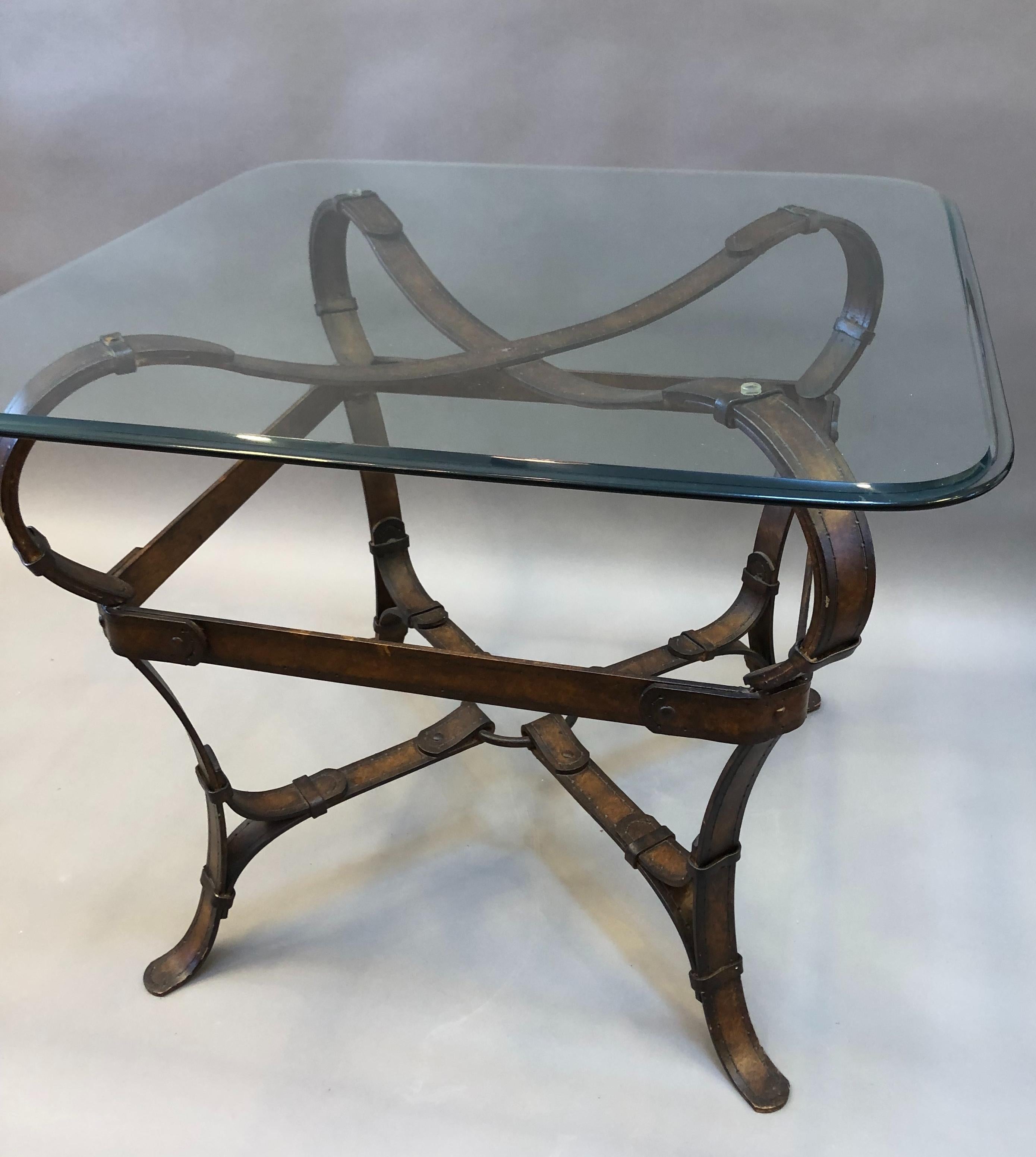 Extraordinary Equestrian style iron and glass side table with curving faux leather harness straps crafted as the main structure and a thick beveled glass top. 20th Century. Measures: 24” H 30” W 30” D 
2 available.
   