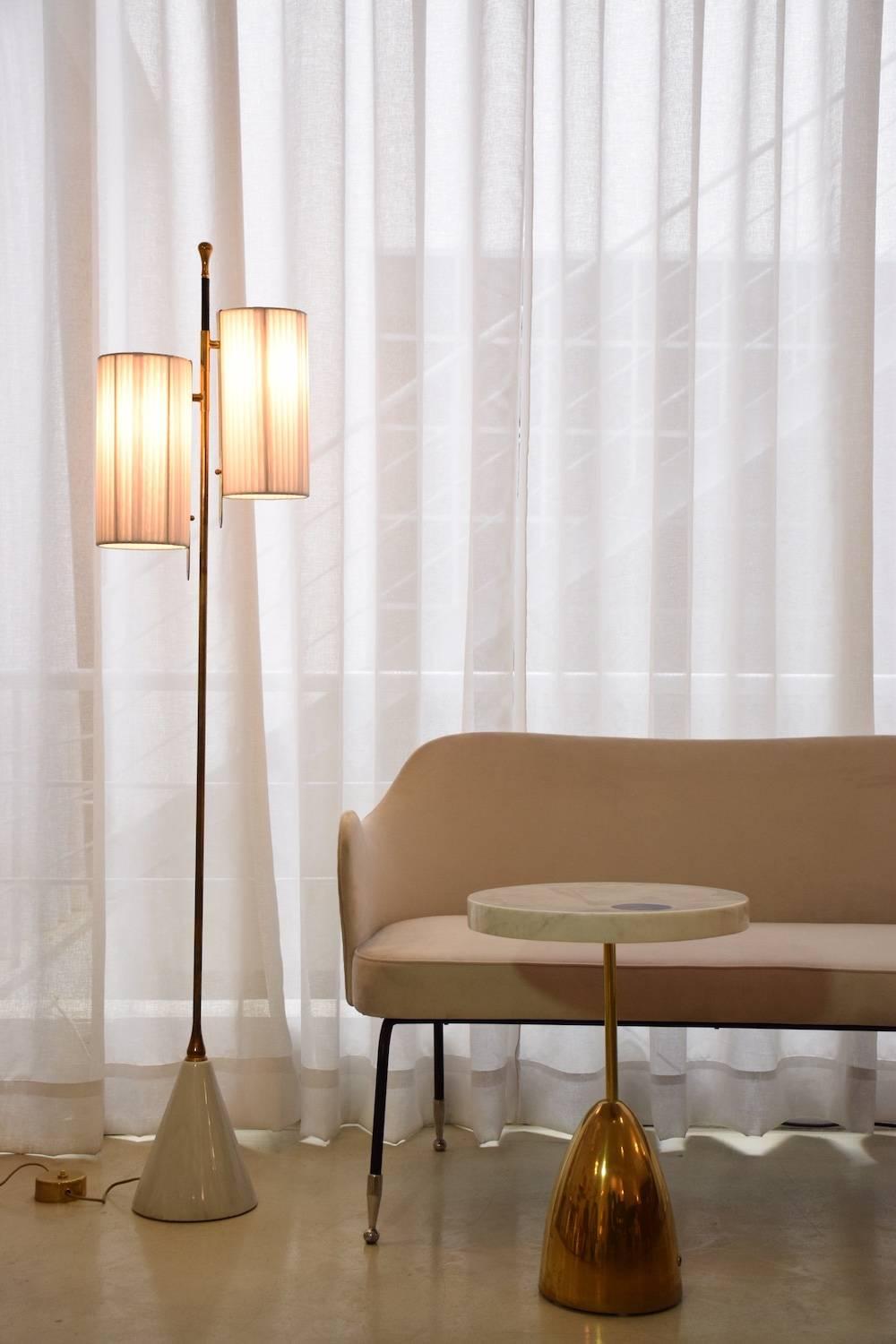 A medium-sized handcrafted floor lamp composed of a solid brass stand adorned with a leather sheathed detail at the top. The long cylinder shades are available in hand-woven wicker or fabric. Option to choose between a black, white, or green marble