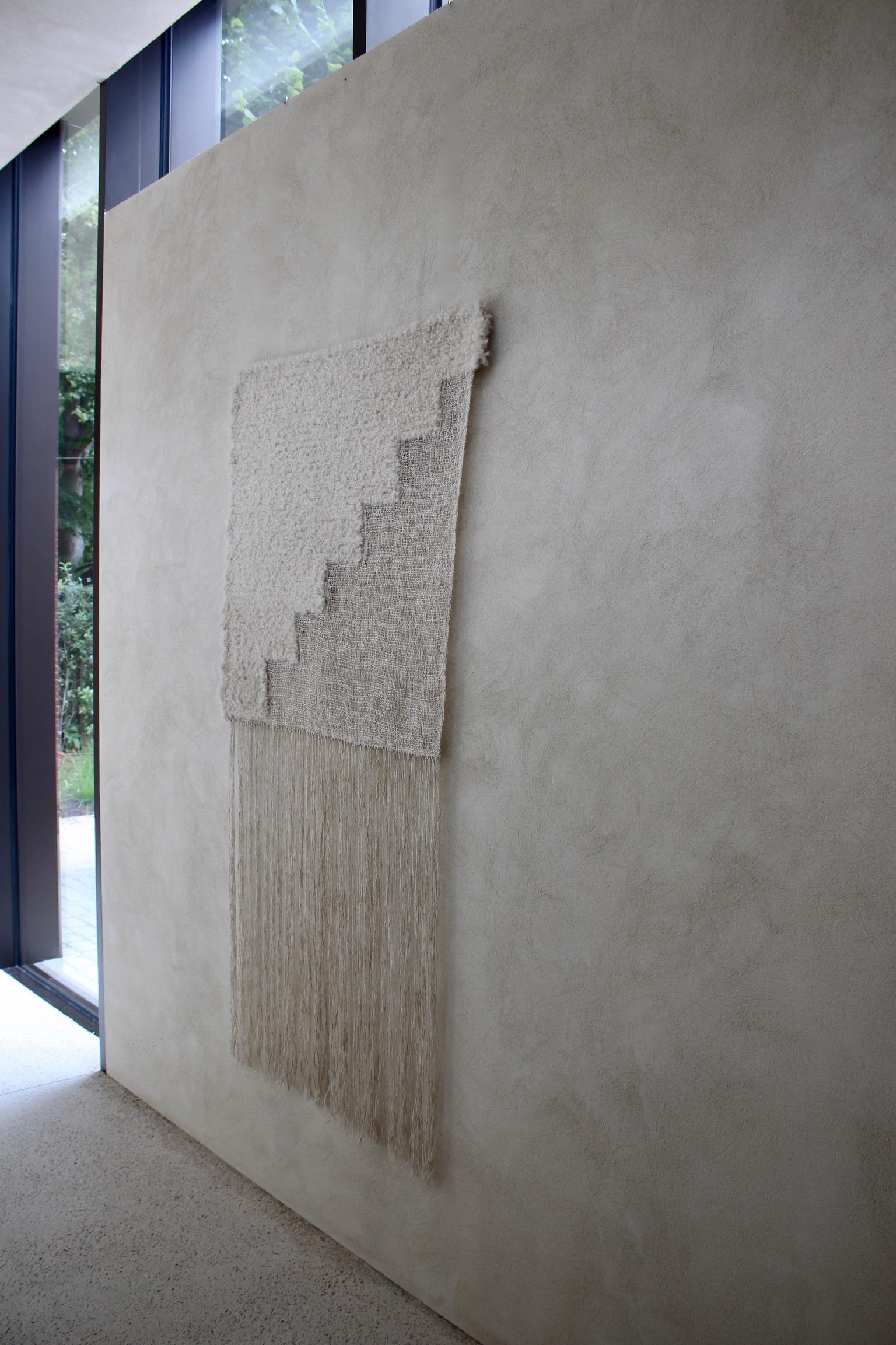 Equipoise #2 Wandskulptur von Delphine Cobbaert
Abmessungen: B 94 x H 180 cm
MATERIALIEN: Wolle, Leinen, Mohair, Jute. 

Delphine Cobbaert ist eine belgische Textilkünstlerin, Designerin und Kunsthandwerkerin. Ihr künstlerischer Weg begann mit einem