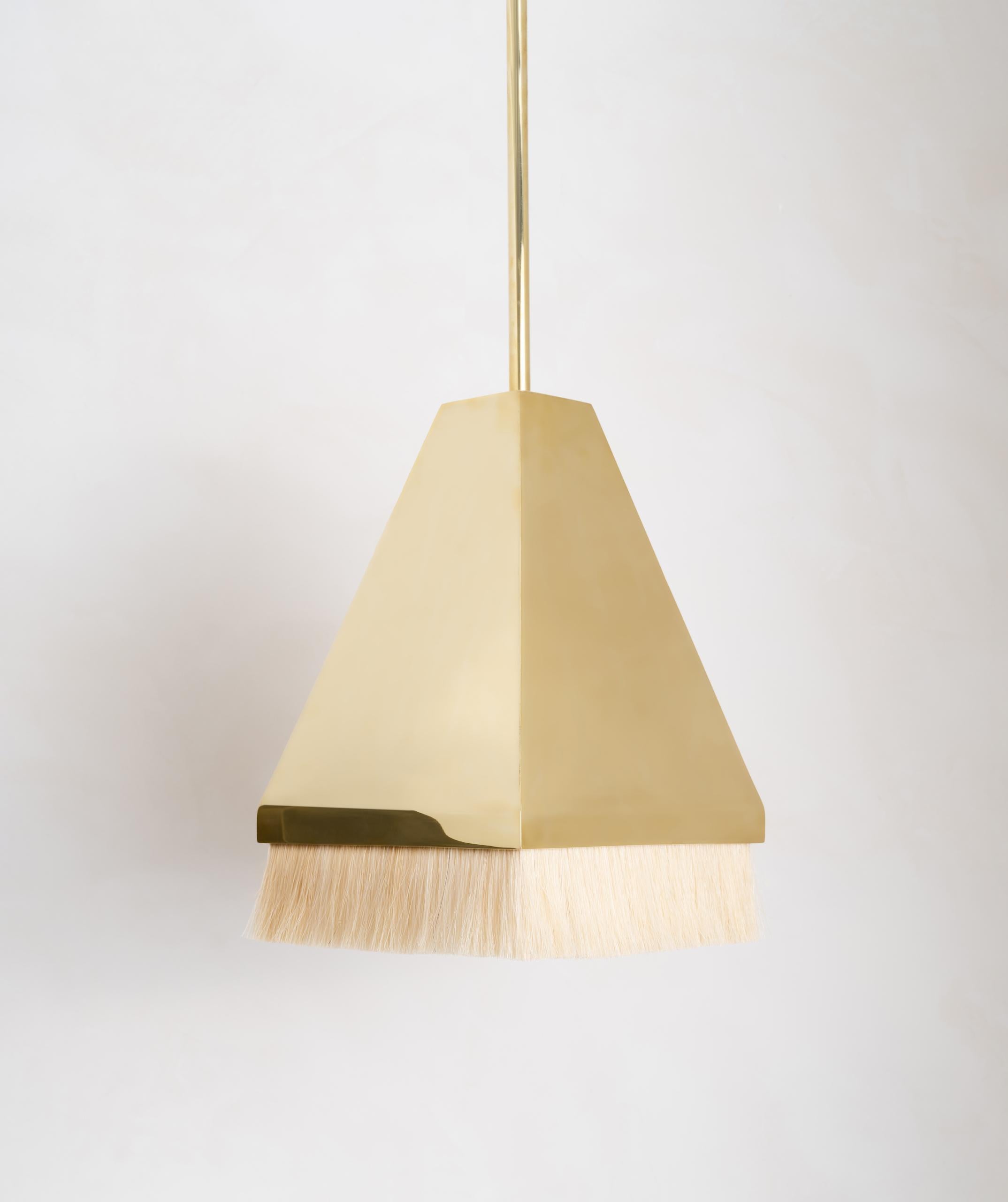 The Equus Pyramid Pendant features meticulously welded, hand-finished brass with a horse hair trim. Available in two sizes, the pendants showcase a complimentary balance between contrasting textures. Down light gives the horse hair an ethereal