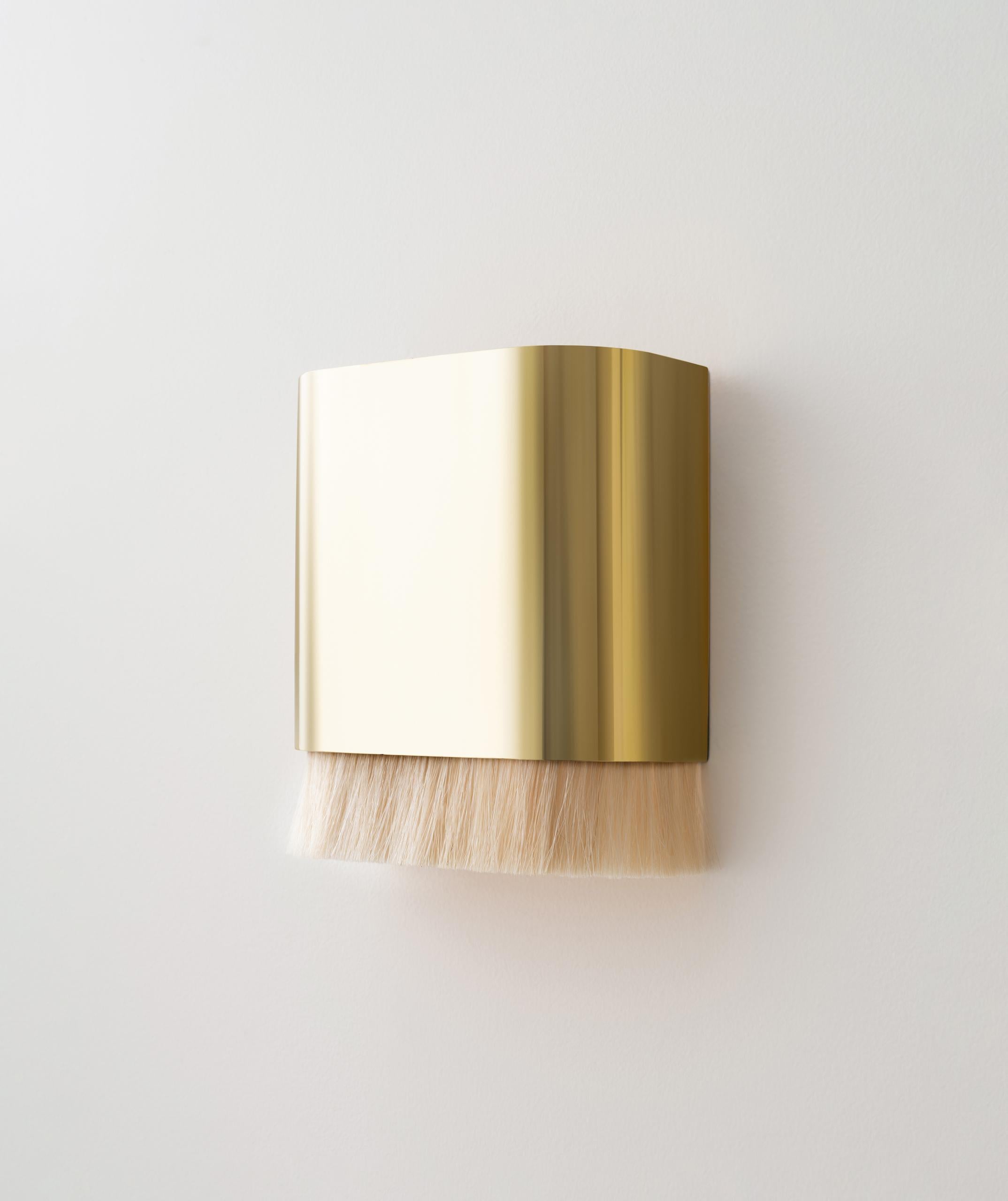 The Equus Sconce features hand-finished brass with a horse hair trim, creating a gentle glow of light. This pairing showcases a balance between contrasting textures and characteristics — horse hair appears soft and malleable but is coarse to the