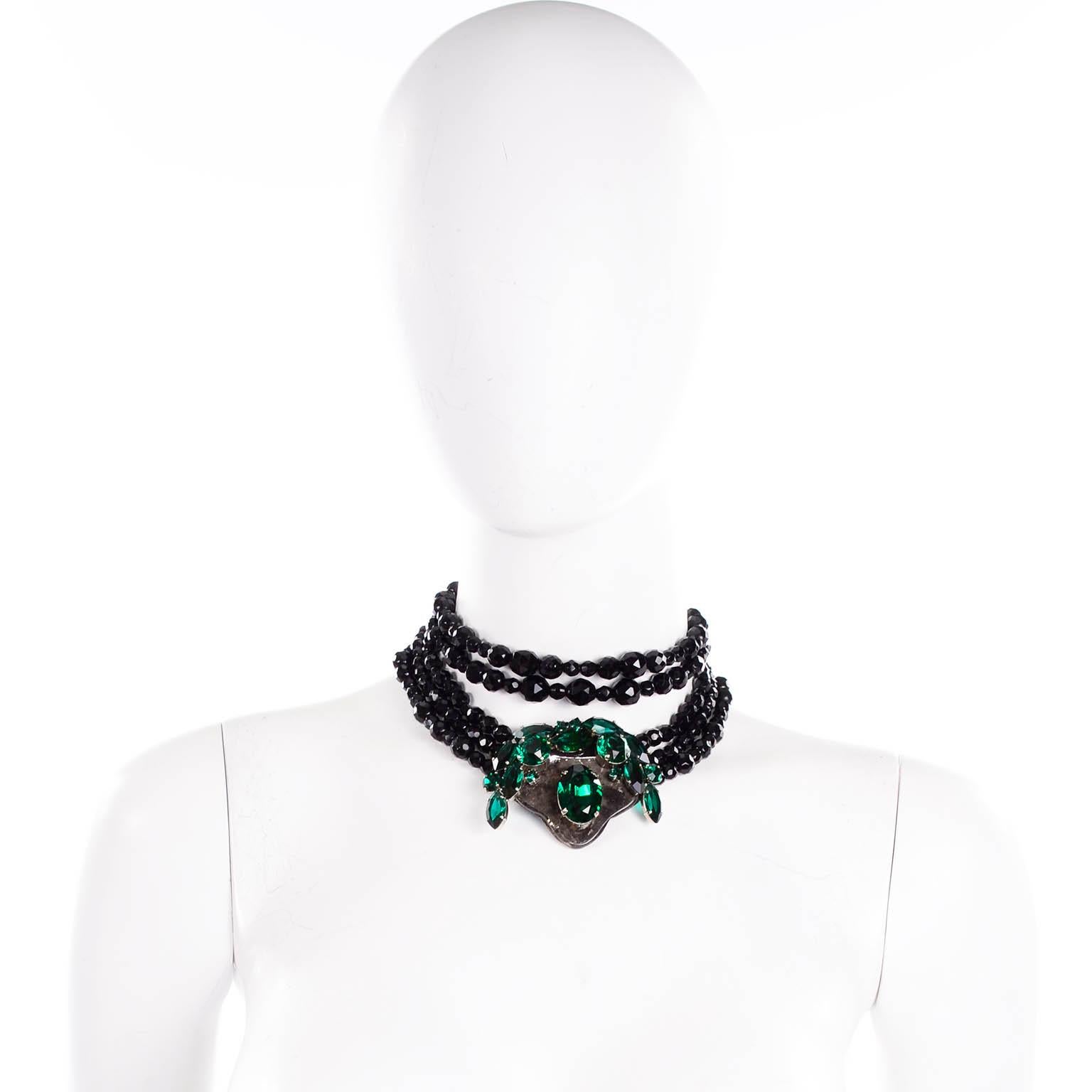This is a dramatic vintage beaded faceted glass cabochon necklace by Emanuel Ungaro Couture inspired by Mughal jewelry. It has multiple strands of alternating sizes of faceted black beads leading to a central pendant with large green stones. Two