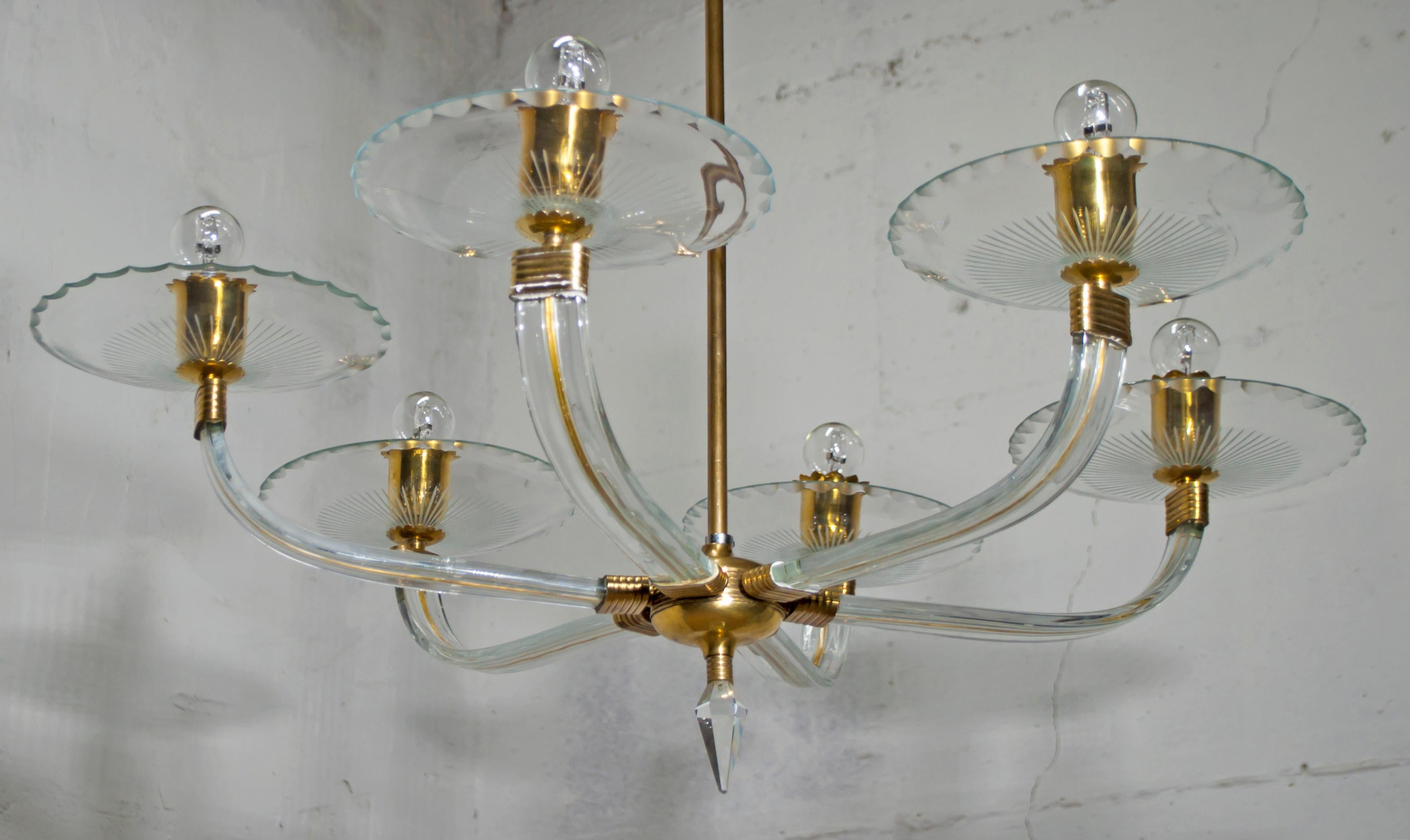 This chandelier from the 1940s in brass and Murano crystal, with 6 lights on hand-engraved crystal plates, with a prism-shaped crystal tip.

This artistic glassware has existed since the mid-thirteenth century.

