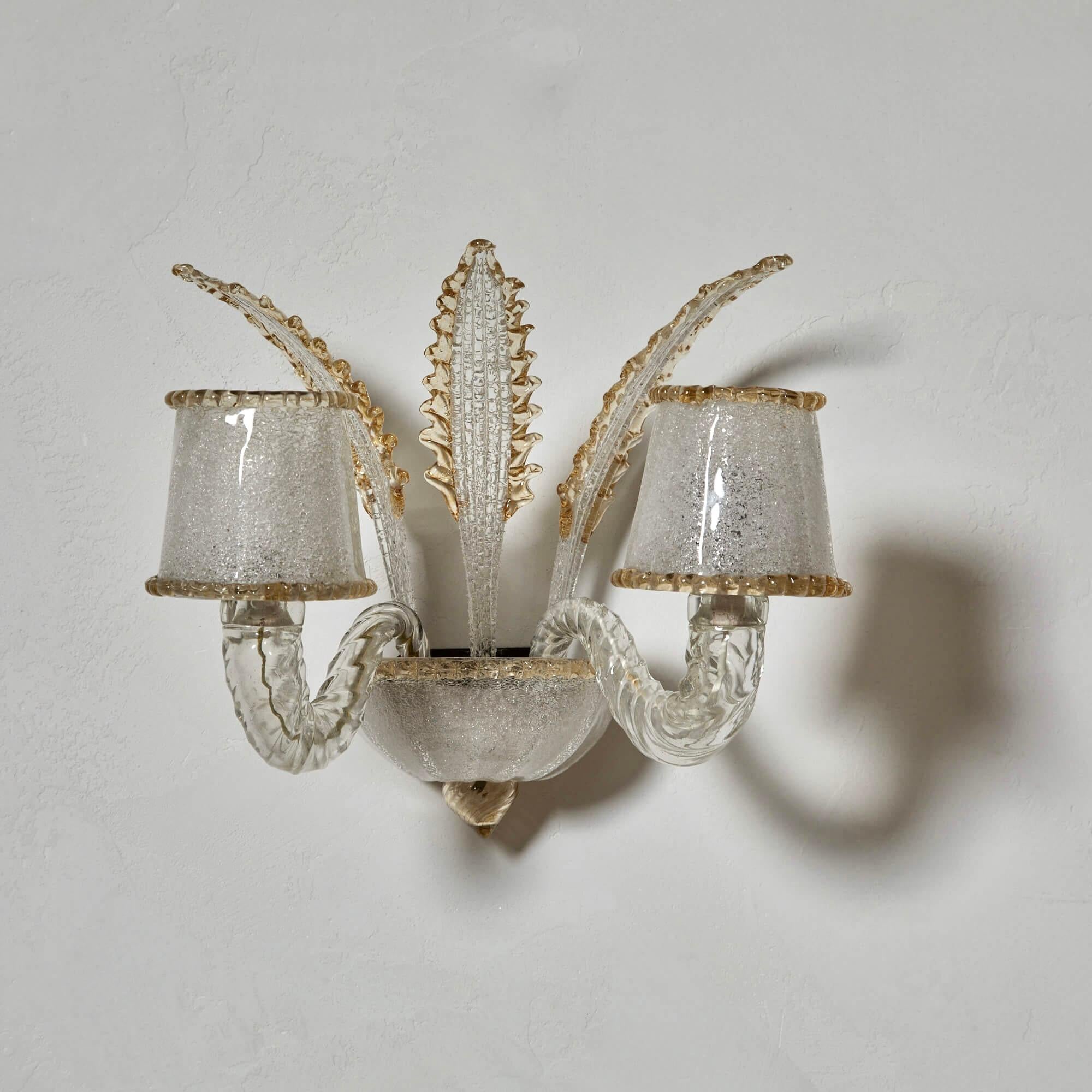 En este candelabro de dos luces, hay muchos detalles característicos de Barovier que admirar. La variedad de texturas y los gruesos y sinuosos brazos que sostienen las pantallas de cristal, ofrecen un audaz contrapunto a las hojas más delicadas y