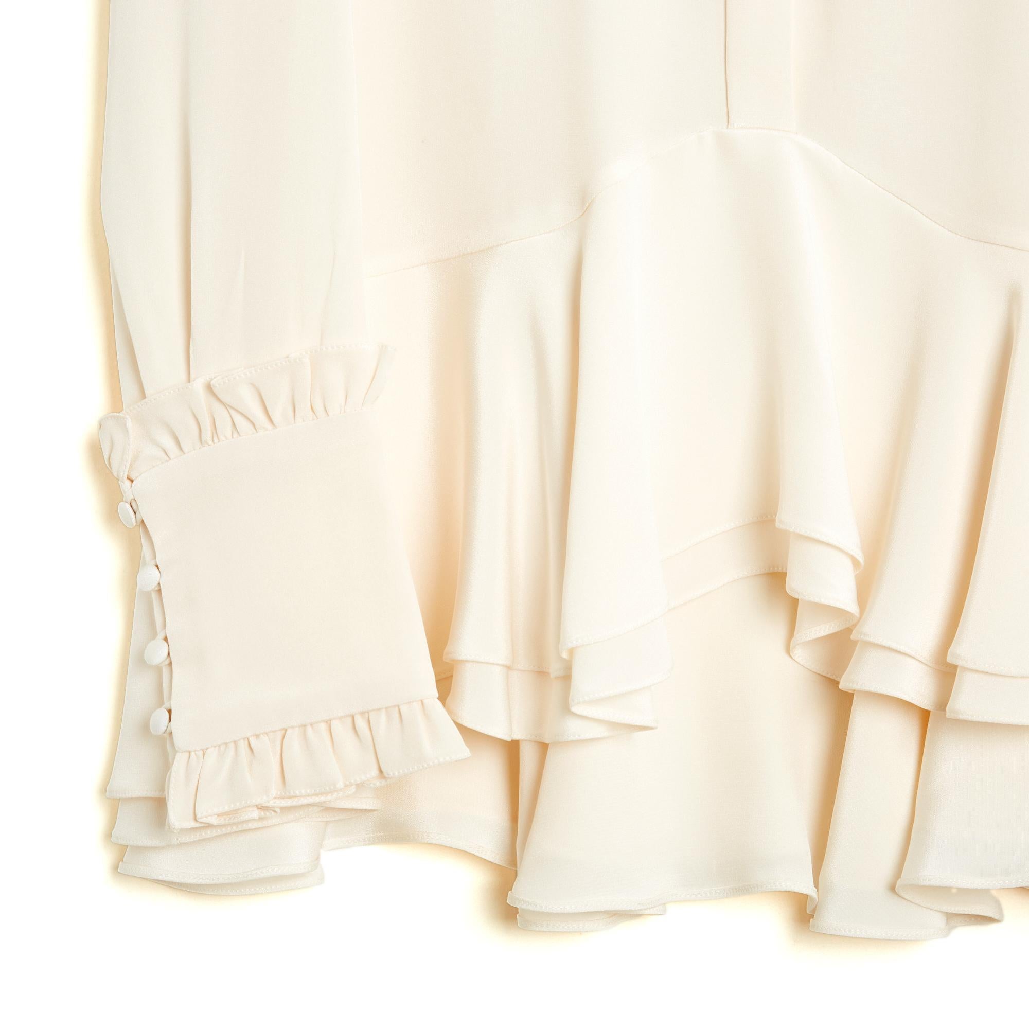 Top blouse Erdem collection SS2016 volume oversize en crêpe de soie écru, col tunique fermé par un bouton habillé et 5 boutons logo cachés, 2 grands volants au bas de la blouse, plus courte devant que dans le dos, manches longues avec larges