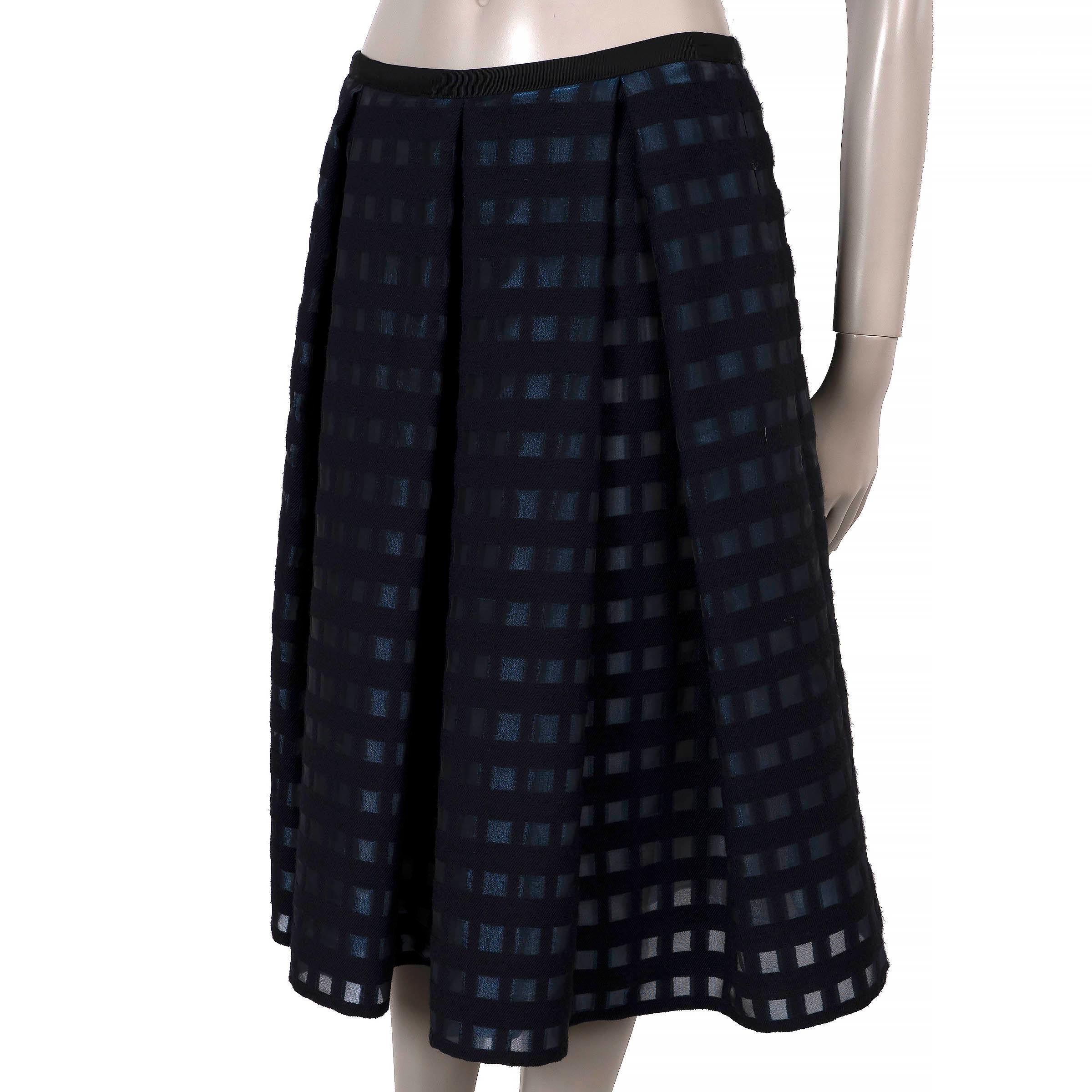 Dieser 100% authentische Erdem Ina Rock ist aus navyblauem Fil-Coupé-Gitter (56% Acryl, 24% Wolle, 12% Polyamid, 8% Polyester) mit halbdurchsichtigen blauen Quadraten und einem dezenten Silberglanz gefertigt. Es zeichnet sich durch eine voluminöse,