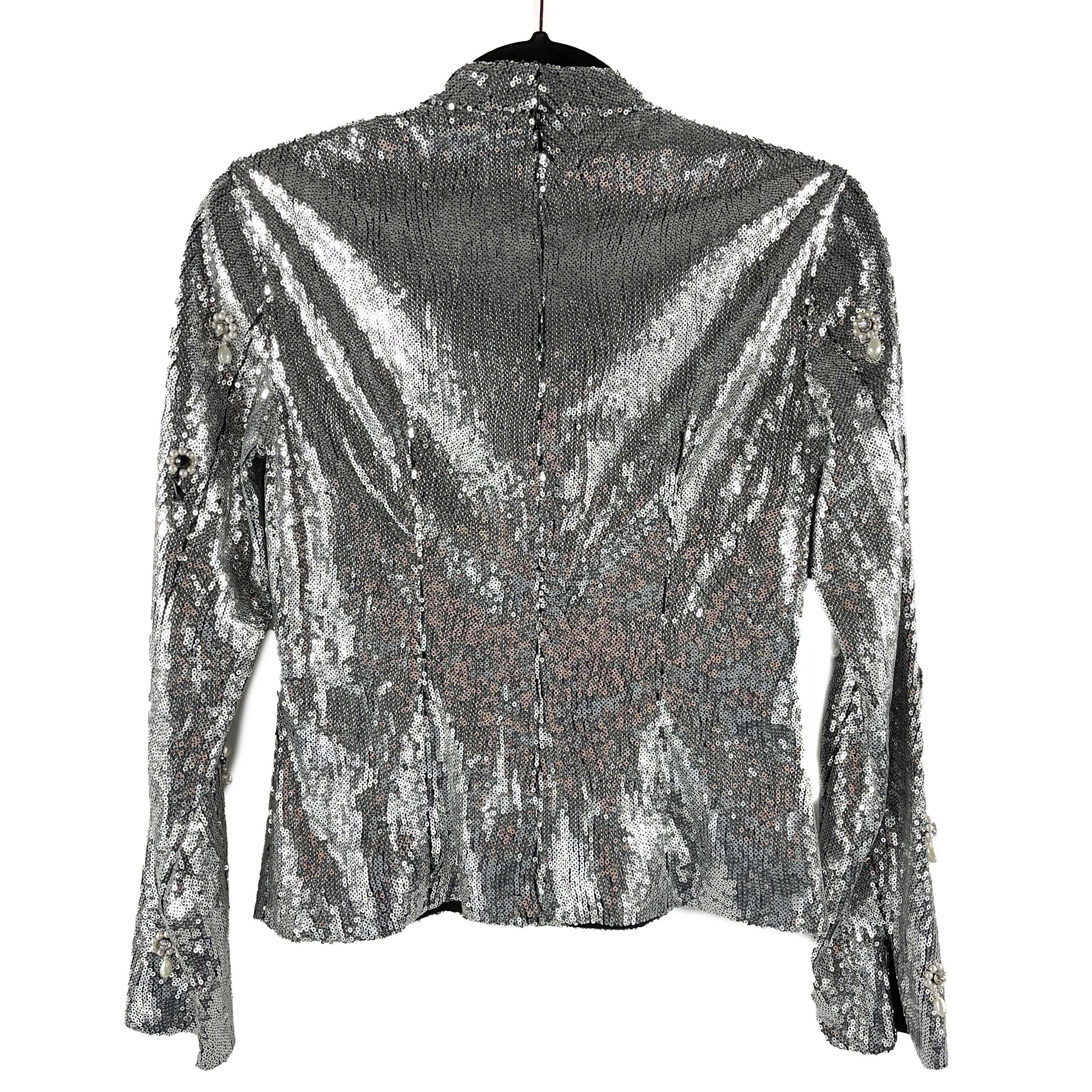 This long sleeved shirt design by Erdem is crafted with polyester and a black silk lining.
Its embellished with silver sequins along with white faux pearls, black beads, and clear crystals that form floral/dangle detailing throughout.
It also
